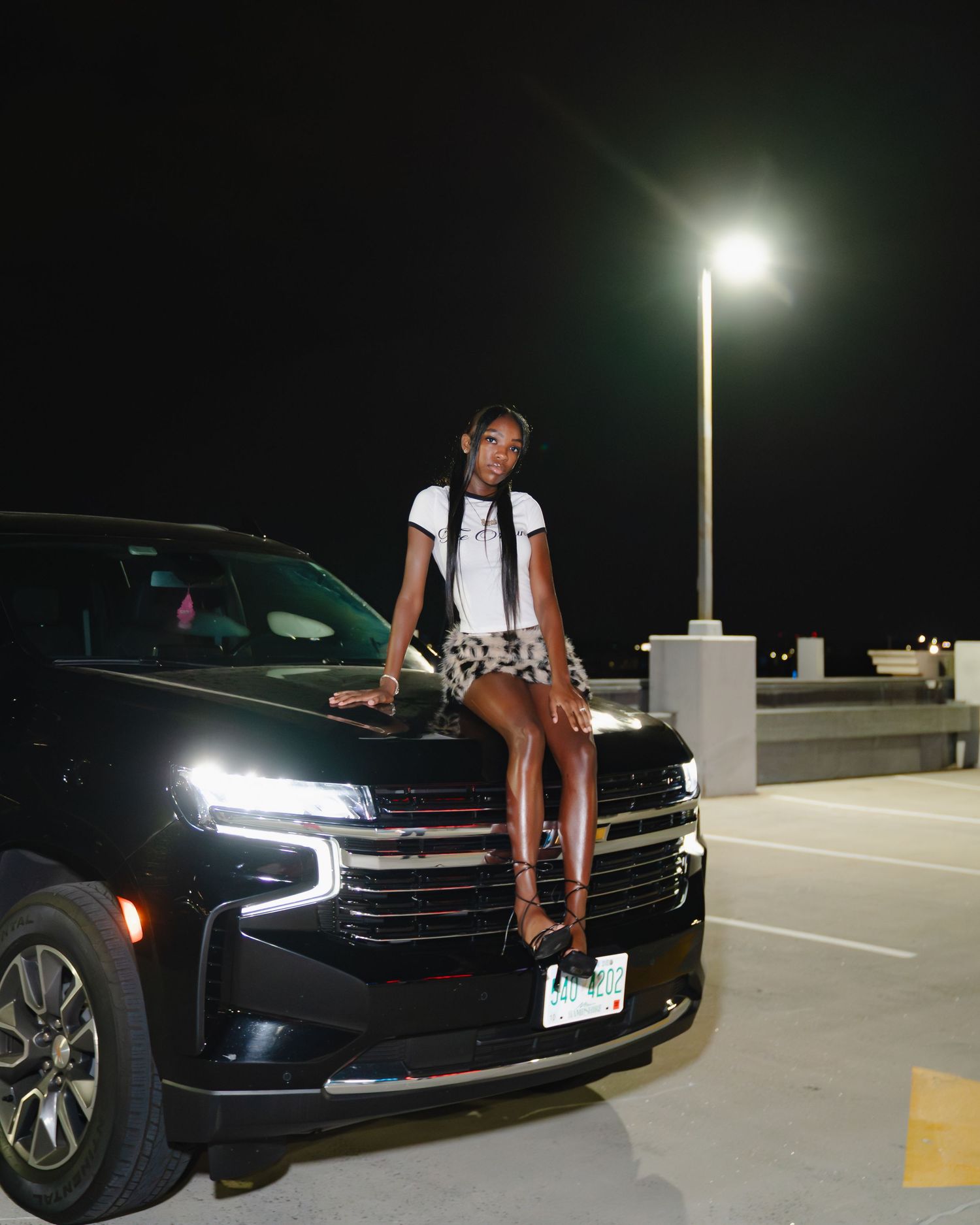 A black Chevrolet Camaro is parked in a dimly lit parking garage at night with its headlights illuminated. Boston MA photographer, Malden MA