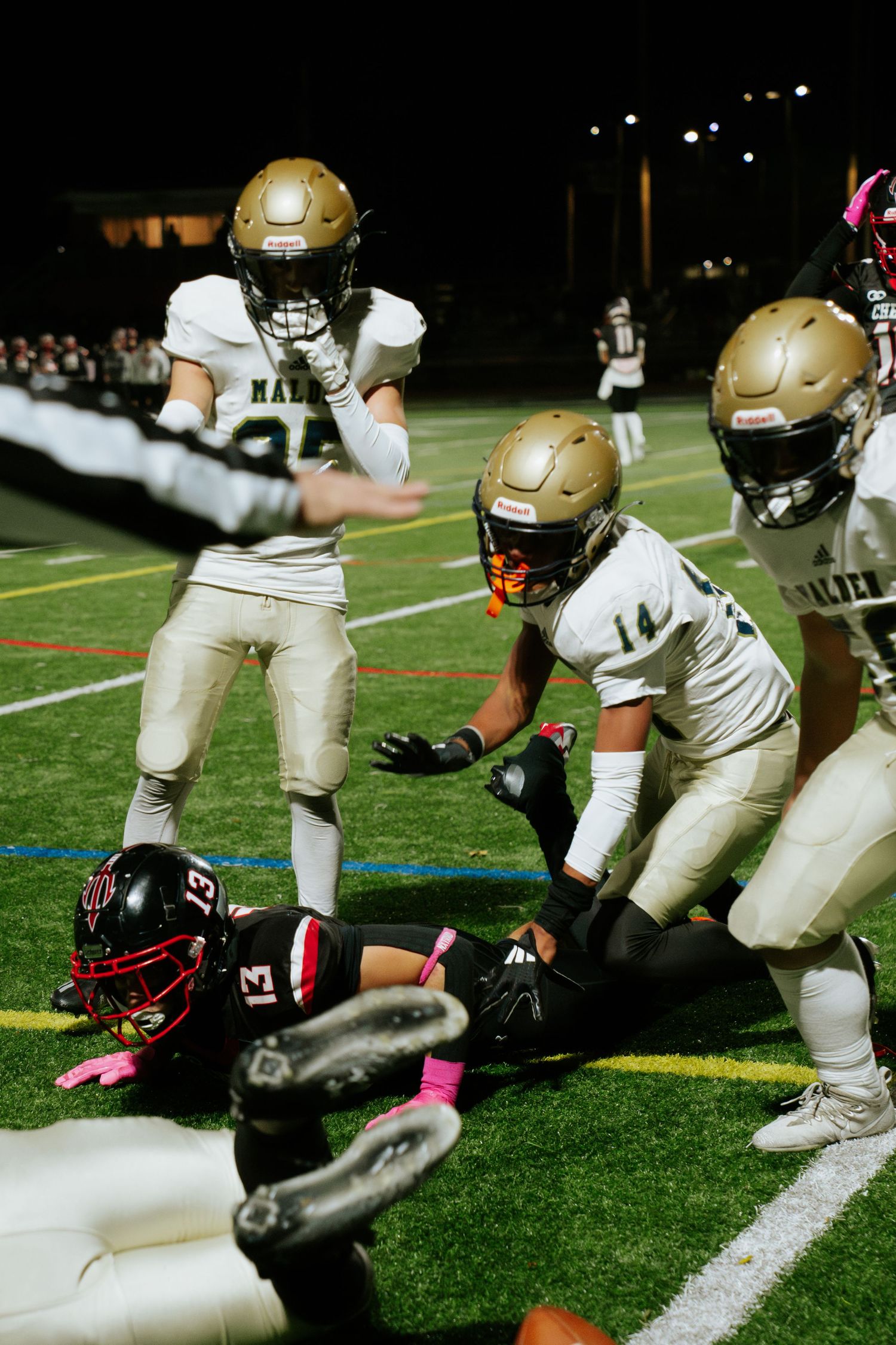 Football players in gold and black uniforms compete for the ball during a nighttime game on artificial turf. Boston photographer, Malden MA.