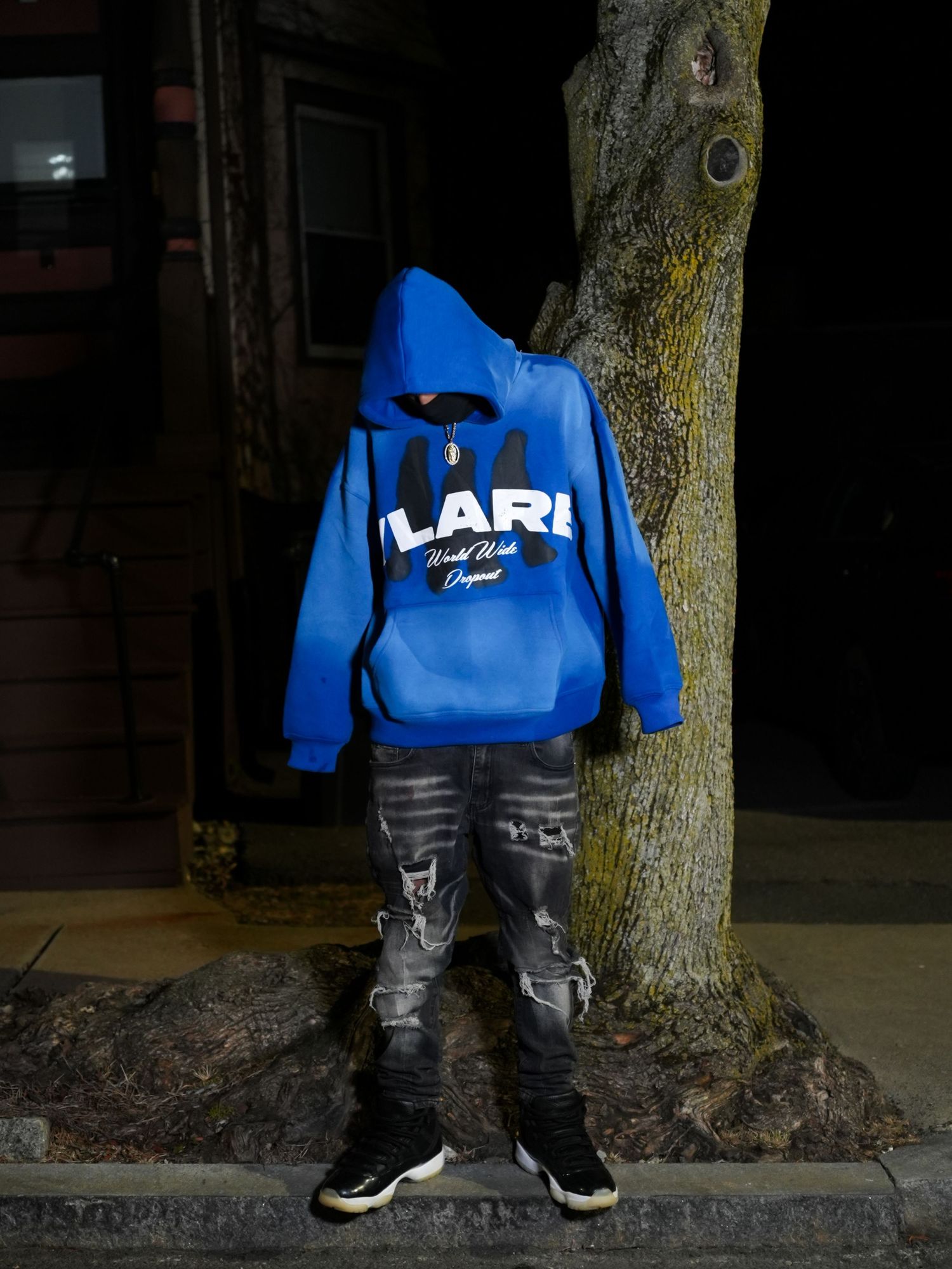 A blue hoodie and dark jeans outfit photographed against a tree trunk in an artistic headless style. Greater Boston Area photographer.