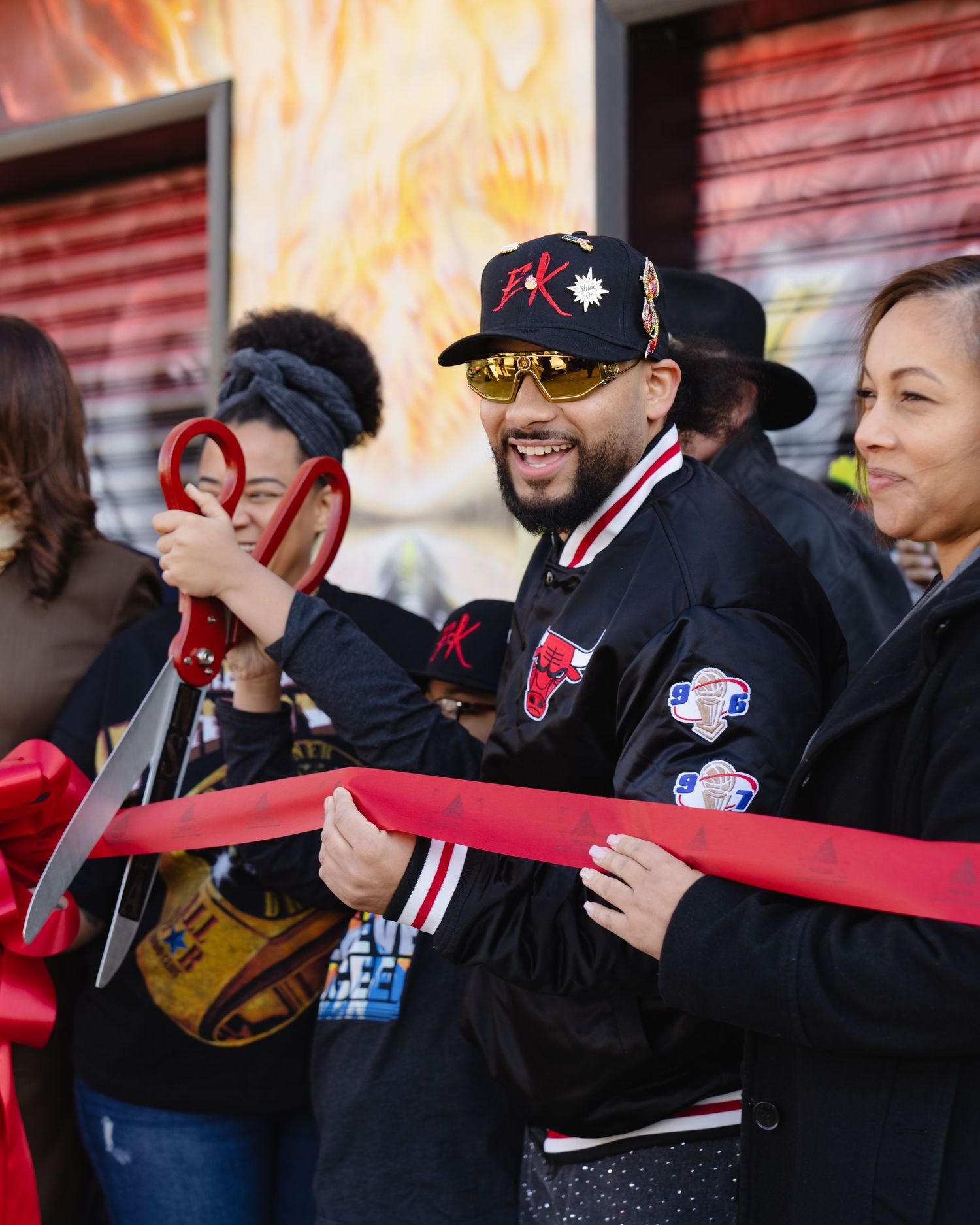 Crowd of spectators cheering and holding up a red ribbon at grand opening. Boston MA photographer, Malden MA and Greater Boston.