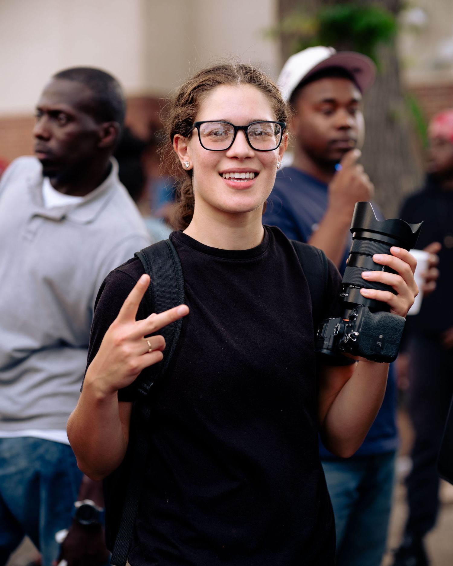 A group of people gathered outdoors with some holding a camera while interacting with each other. Boston MA photographer, Malden MA.