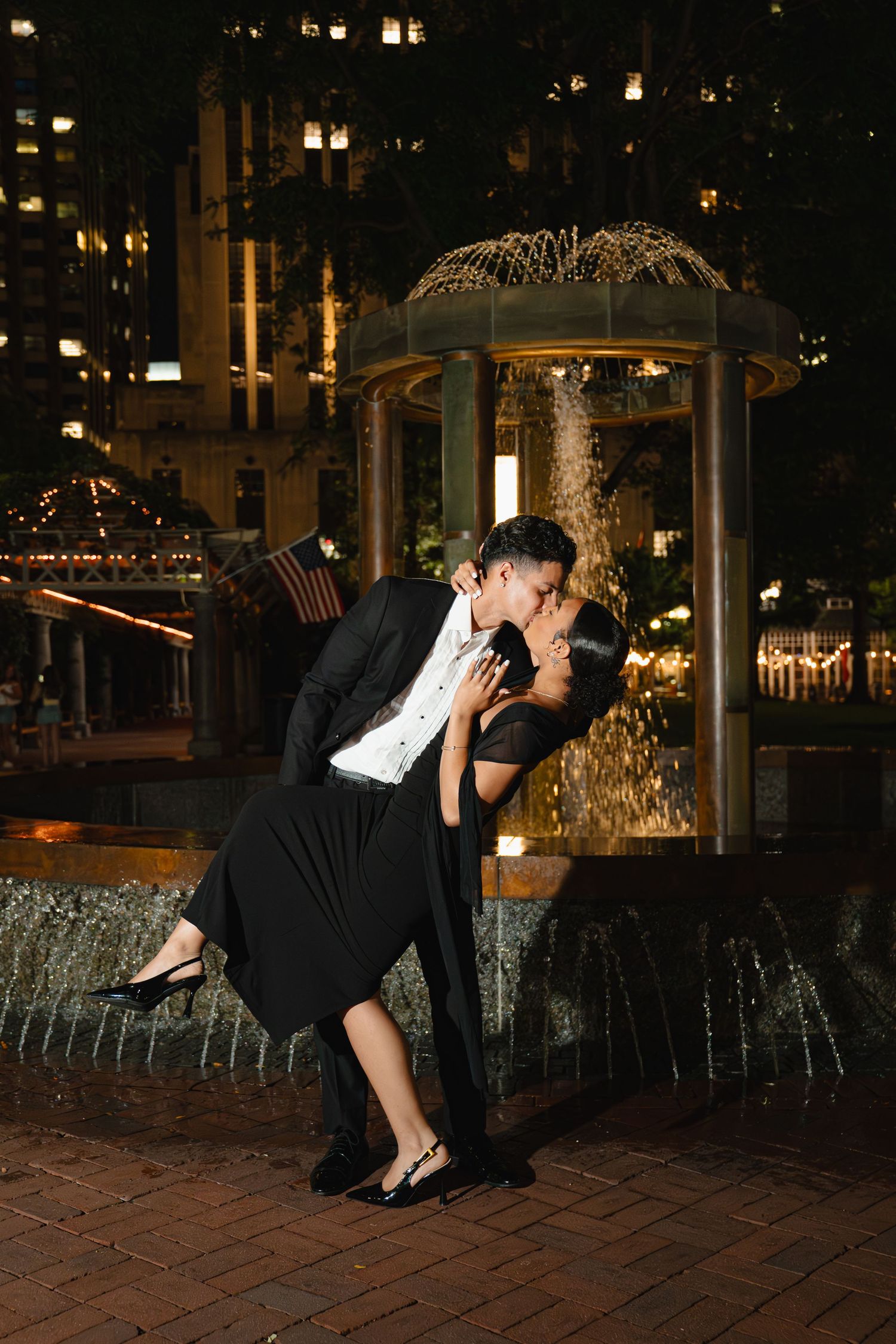 Couple in formal attire performs romantic dip pose by illuminated fountain at night. Boston MA photographer, Malden MA and Greater Boston.