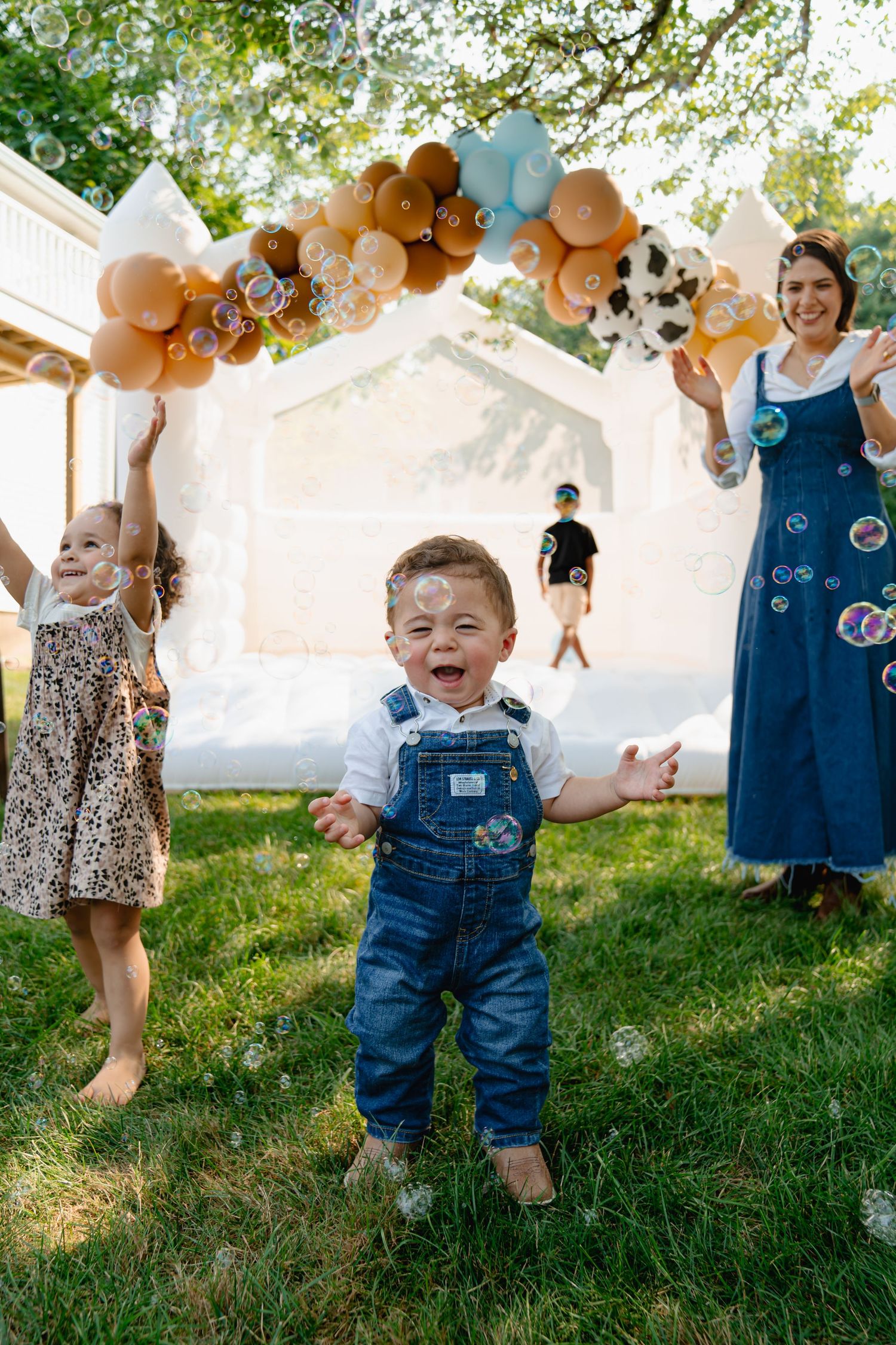 Candid photo showing a small child playing outdoors near white tents with orange balloon decorations. Boston MA photographer, Malden MA.