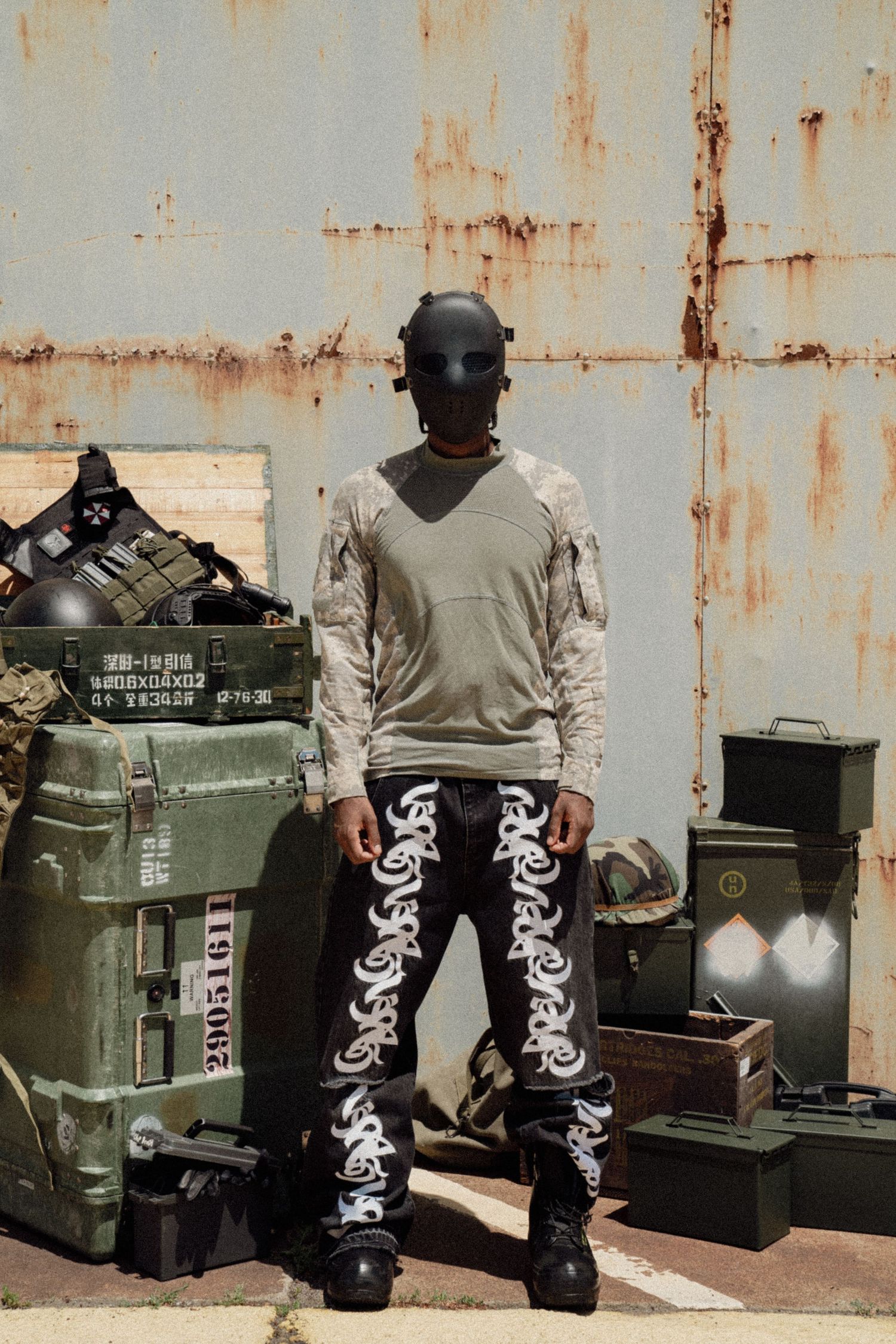Military personnel in tactical gear inspects green ammunition crates with white markings on a rusty metal background. Boston MA photographer