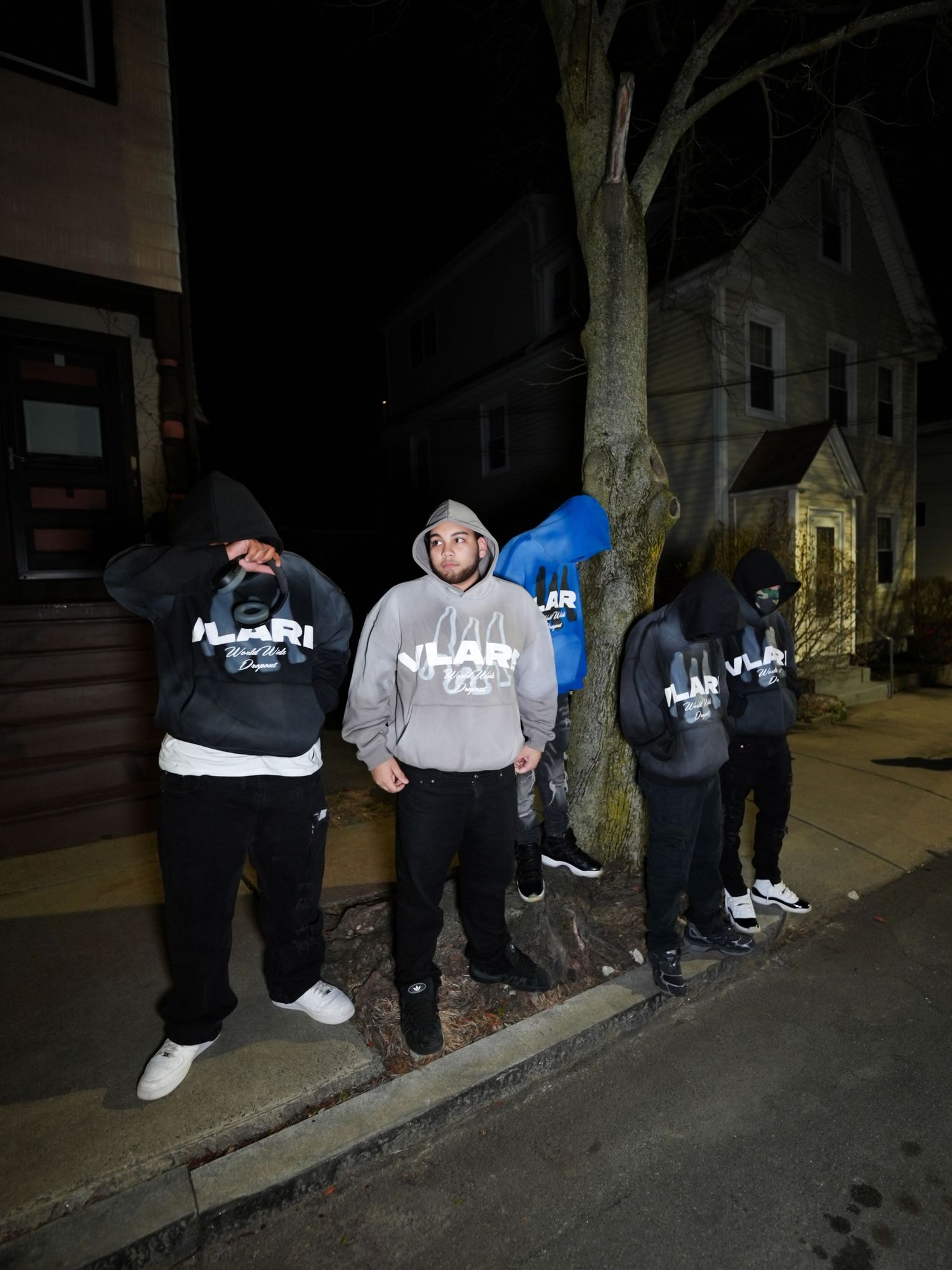 Group of people sitting on a curb at night wearing dark hoodies and casual clothing. Boston MA photographer, Malden MA & Greater Boston Area