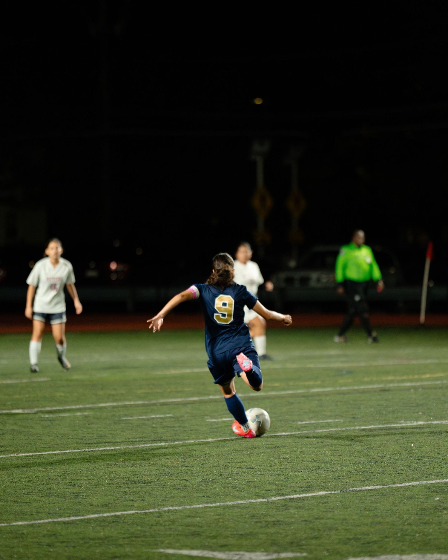 Soccer player sliding to kick a ball on an illuminated artificial turf field at night. Boston MA photographer, Malden MA and Greater Boston.