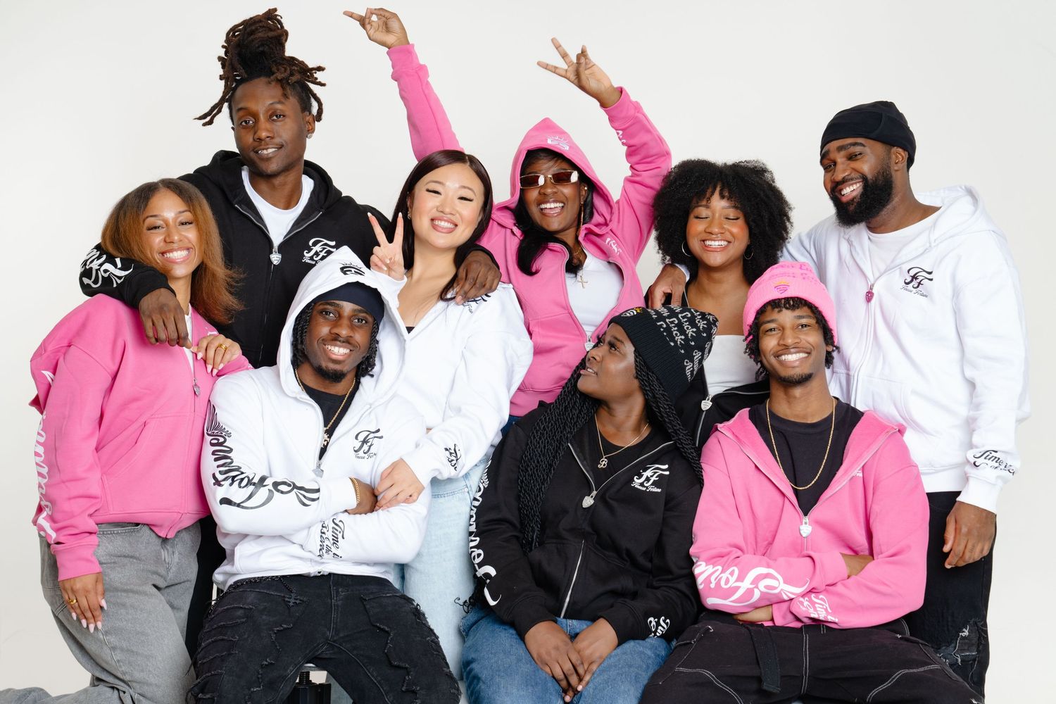 A group of people wearing pink and white outfits pose together in a fun and energetic photo shoot. Boston MA photographer, Malden MA.