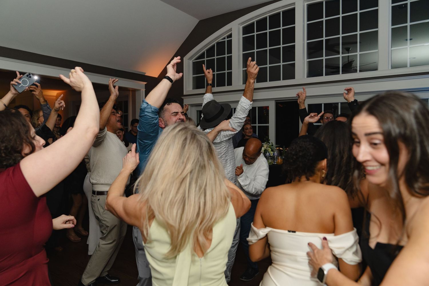 Wedding guests dance together on a crowded dance floor during an evening reception celebration. Greater Boston Area photographer, Malden MA.