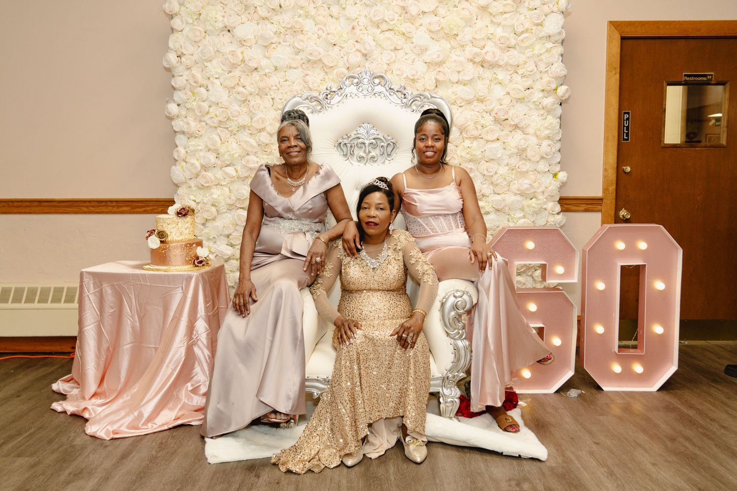 A group of women in elegant champagne and blush colored dresses pose together on a couch for birthday. Boston MA photographer, Malden MA.