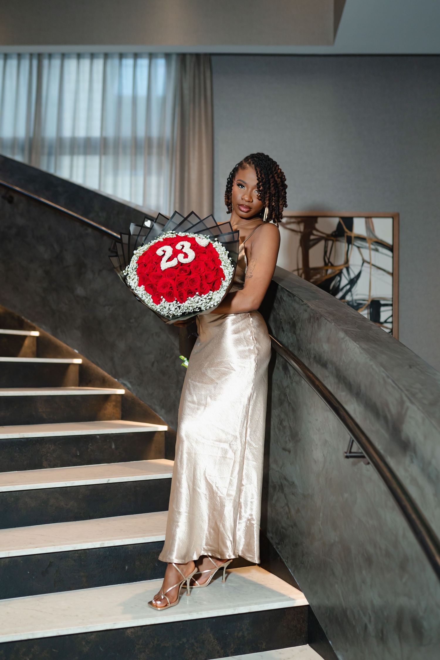 Artistic photos on curved staircase featuring someone in an elegant white dress holding a red number sign. Greater Boston Area photographer.