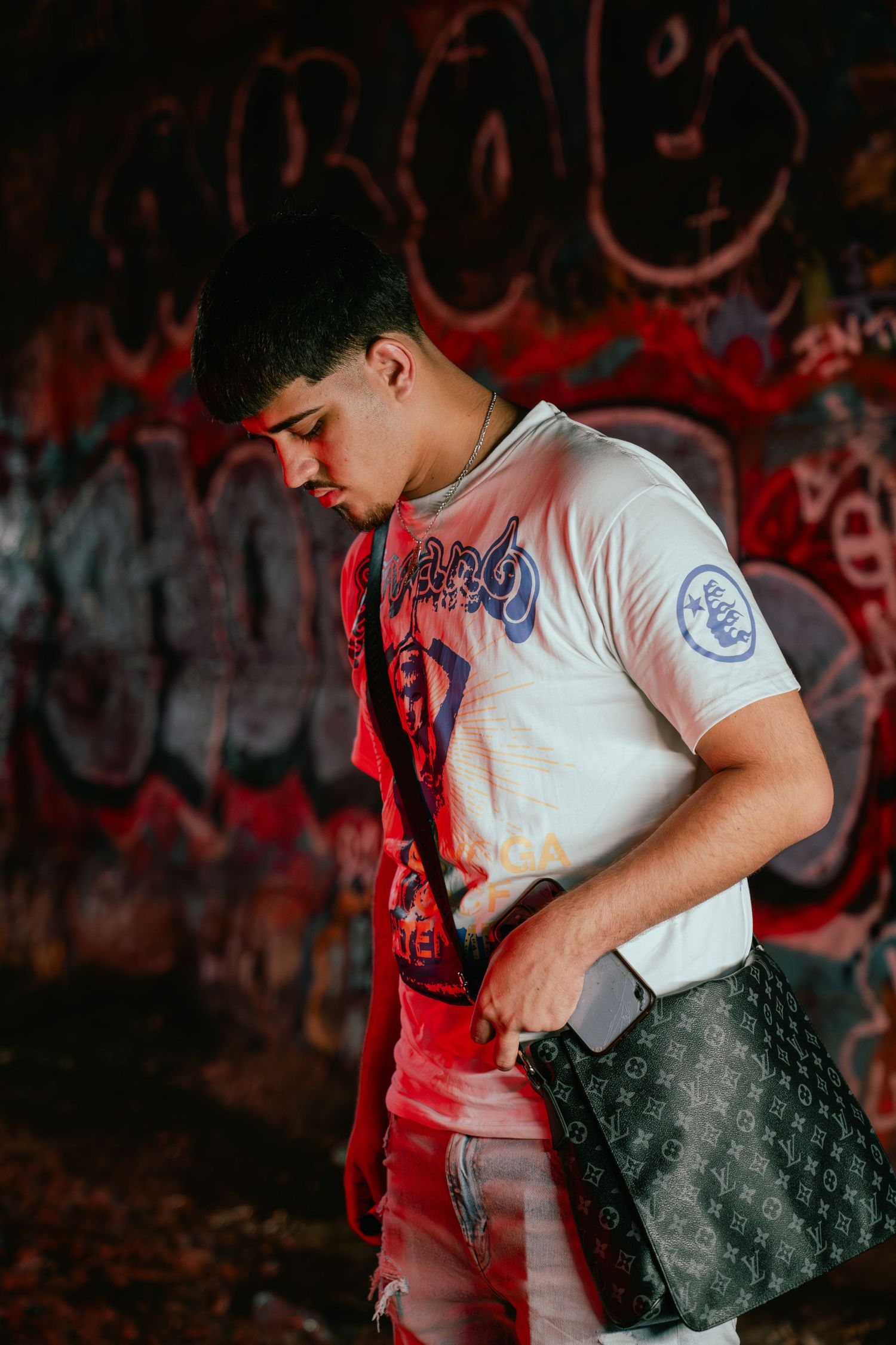 Urban photoshoot with designer handbag against graffiti wall in dramatic red lighting. Greater Boston Area photographer, Malden MA.