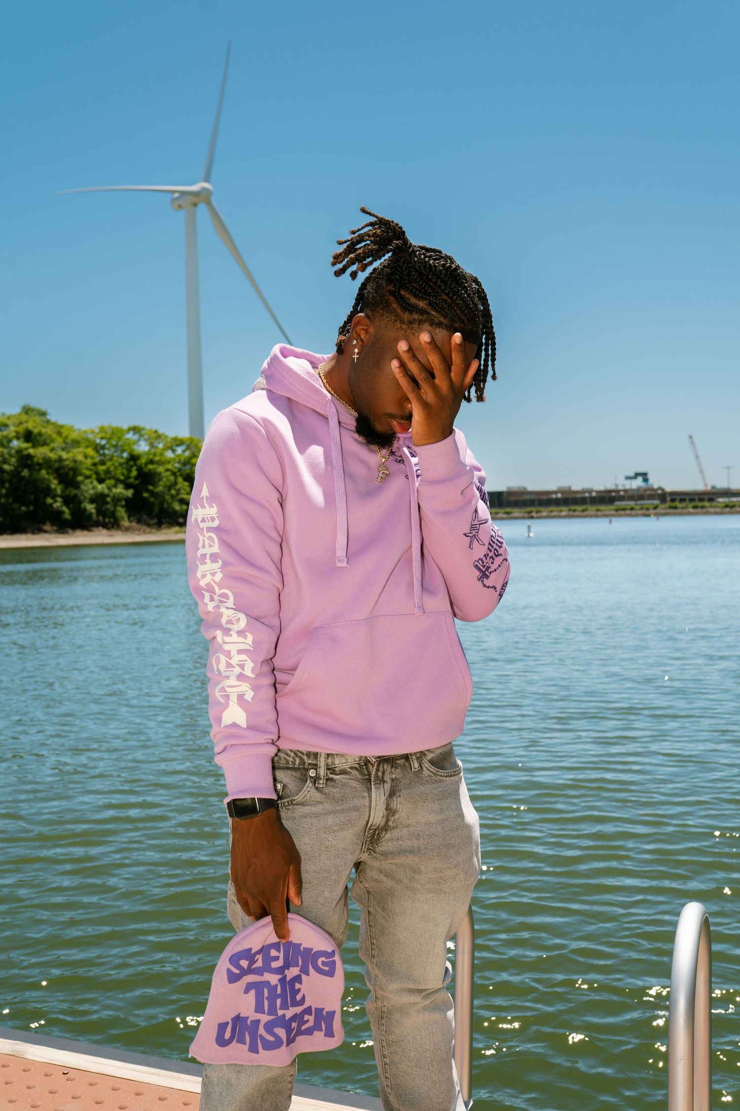 Waterfront fashion shoot featuring pink hoodie against lake and wind turbines. Boston MA photographer, Malden MA and Greater Boston Area.