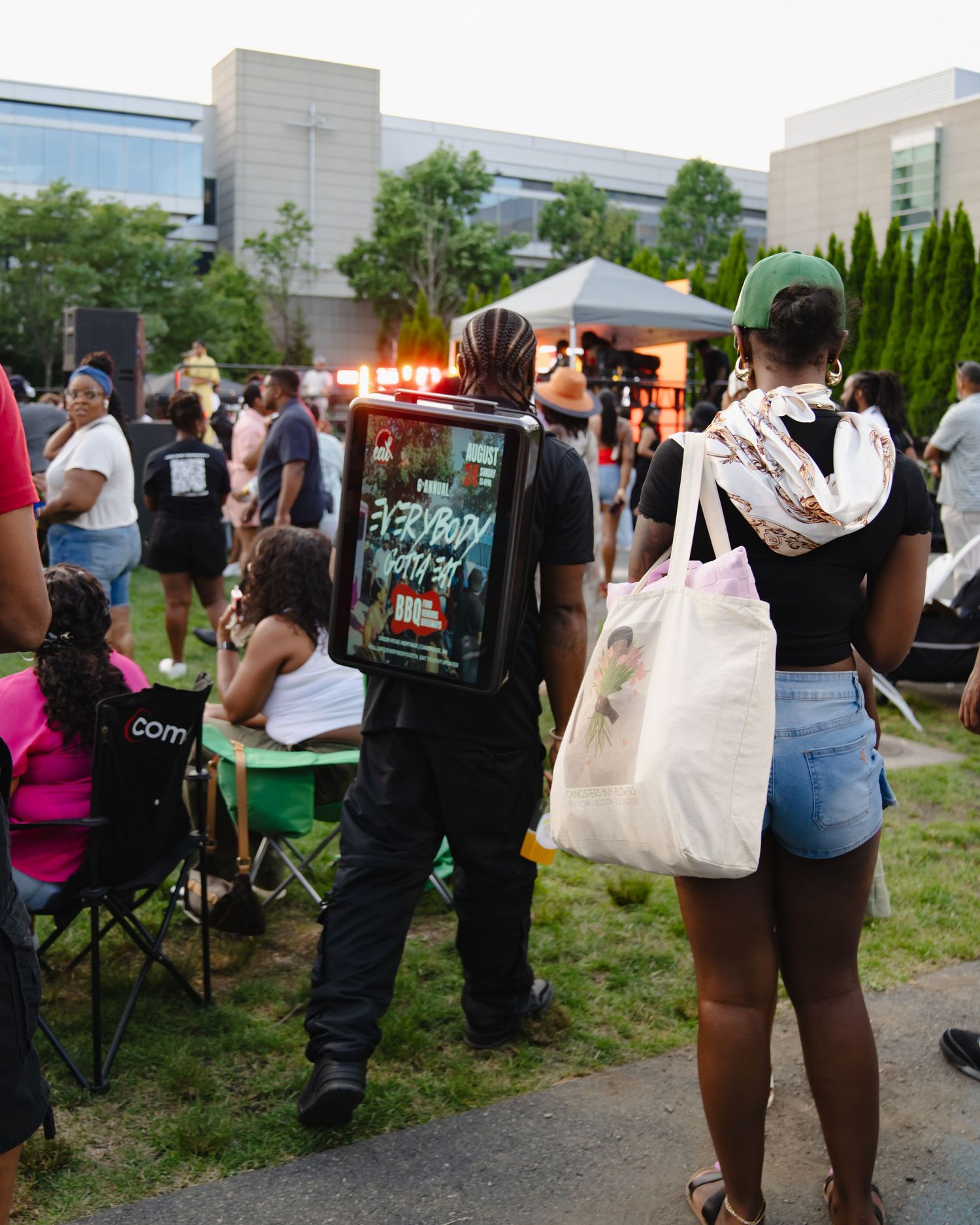 People gather at an outdoor event with lawn chairs and shopping bags as dusk approaches. Boston MA photographer, Malden MA, Greater Boston.