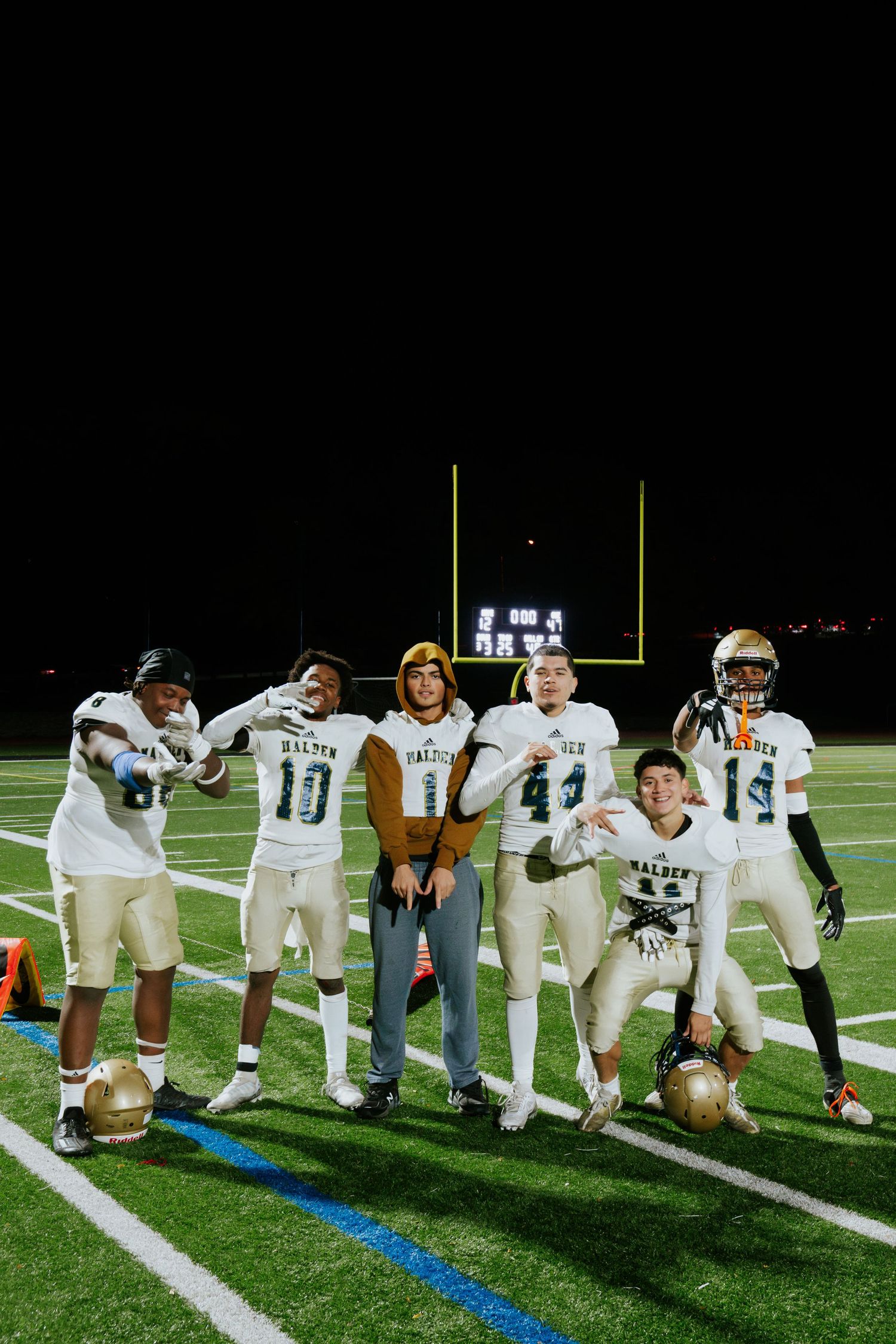 High school football players pose together on the field at night after a game. Boston MA photographer, Malden MA & Greater Boston Area.