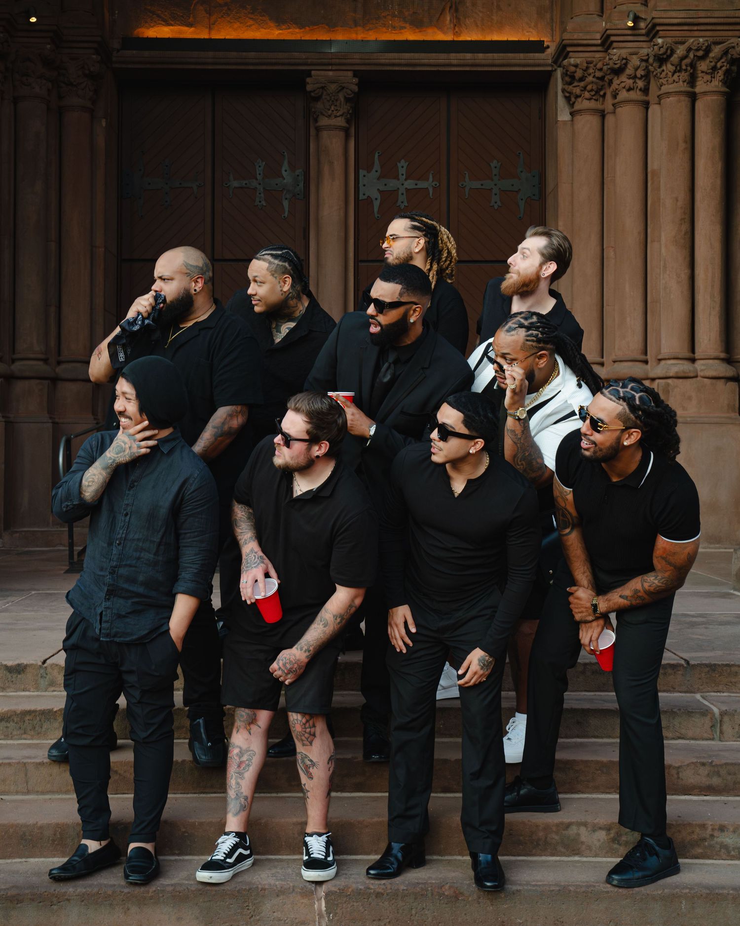 A group of men in black suits sit casually on stone steps while posing for a candid photo. Boston MA photographer, Malden MA, Greater Boston