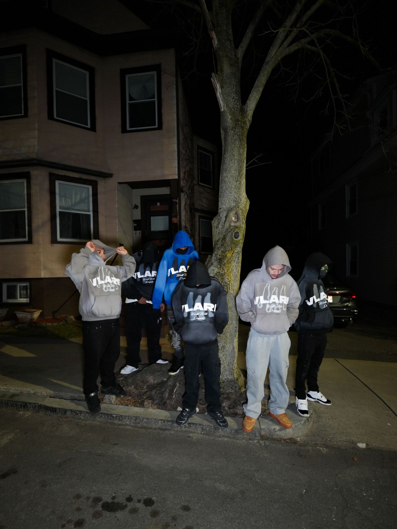 A group of people in hooded sweatshirts gather in a dimly lit outdoor area at night. Boston MA photographer, Malden MA & Greater Boston Area