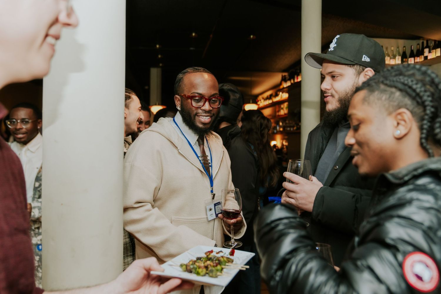 People gathered at a dimly lit social event with drinks and conversation. Boston MA photographer, Malden MA & Greater Boston Area.