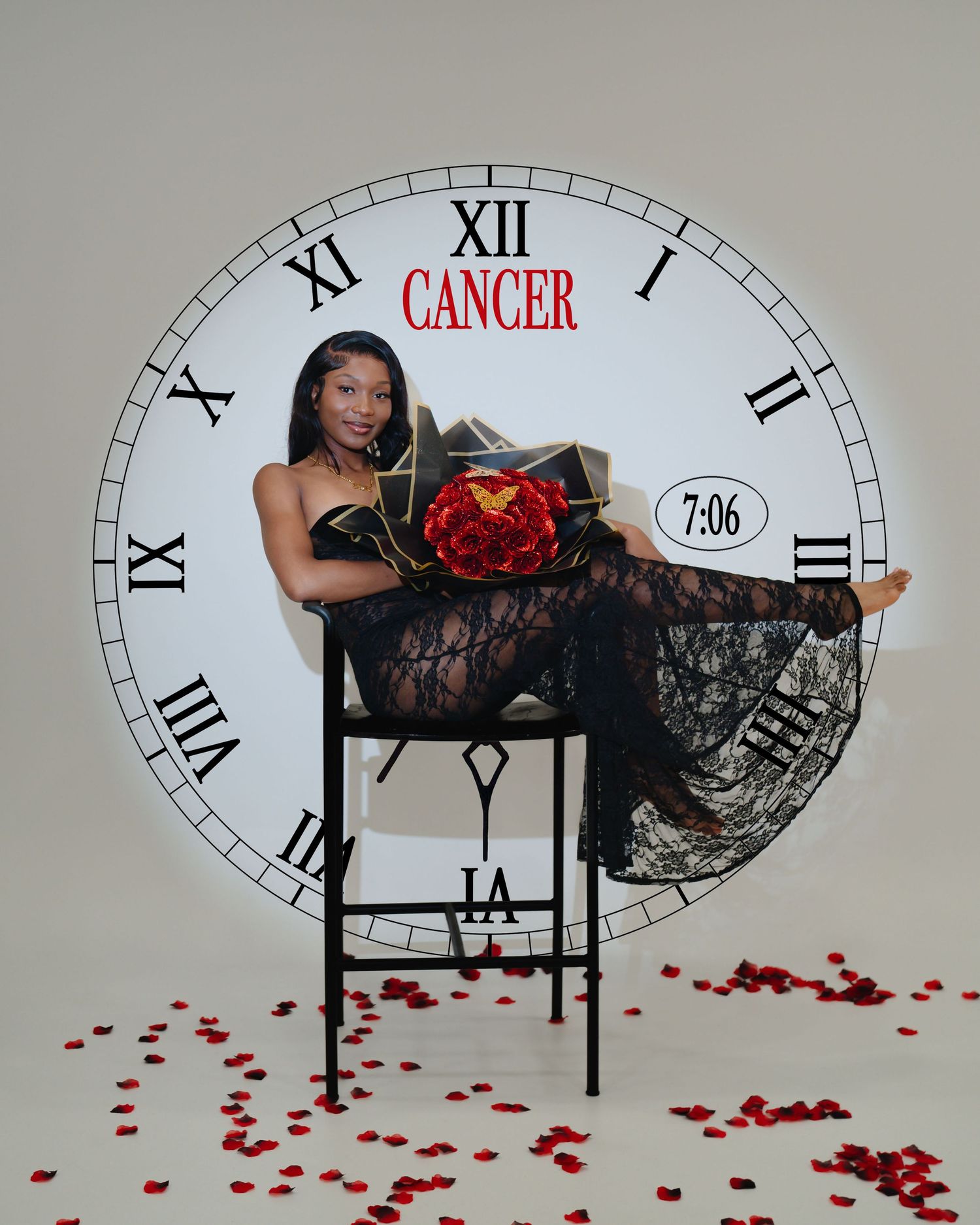 Artistic photo showing a person in black lace reclining on a table against a clock face with scattered rose petals. Boston  MA photographer.