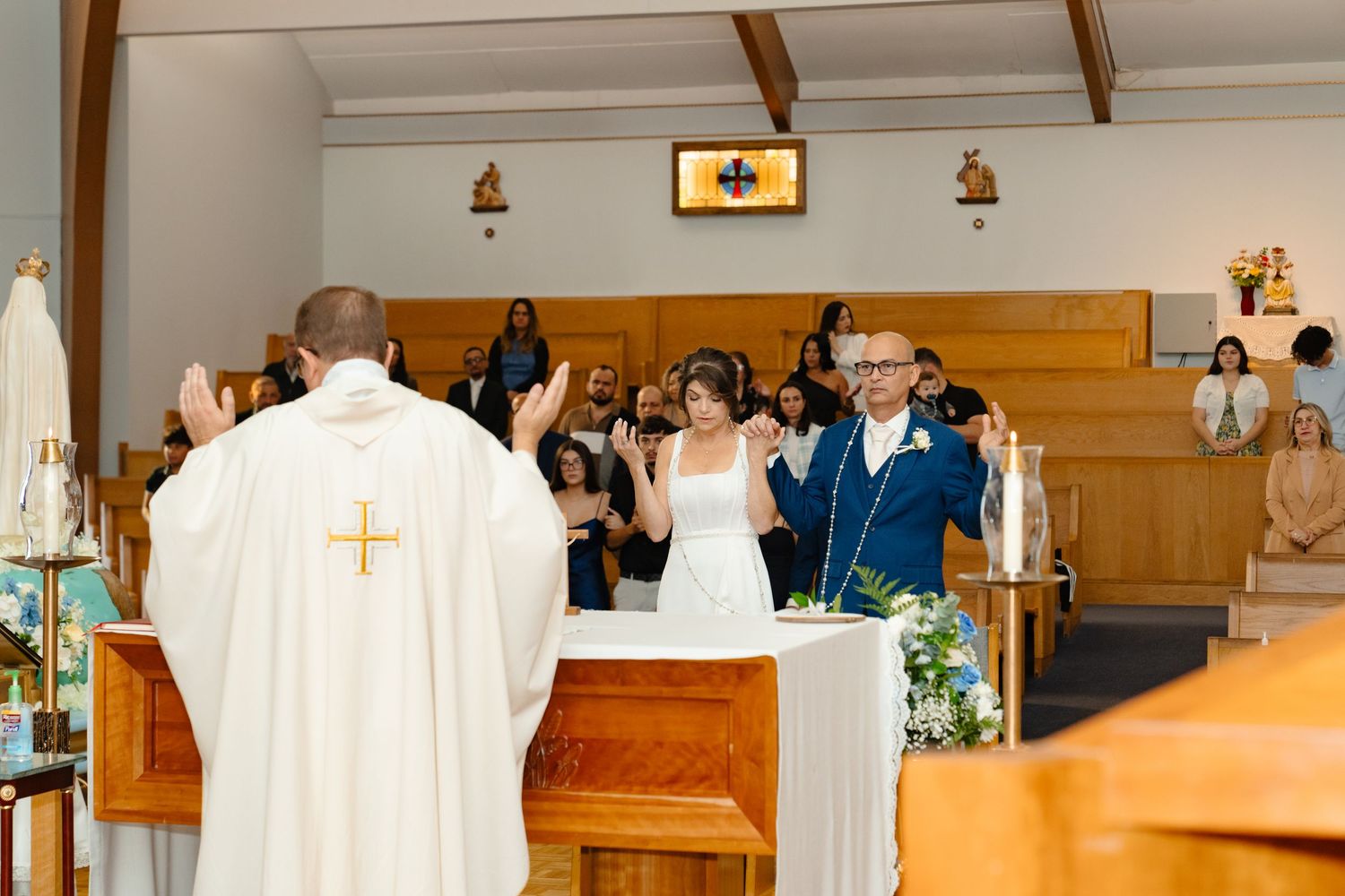 A wedding anniversary taking place in a church with people in white robes standing at the altar. Boston MA photographer, Malden MA.