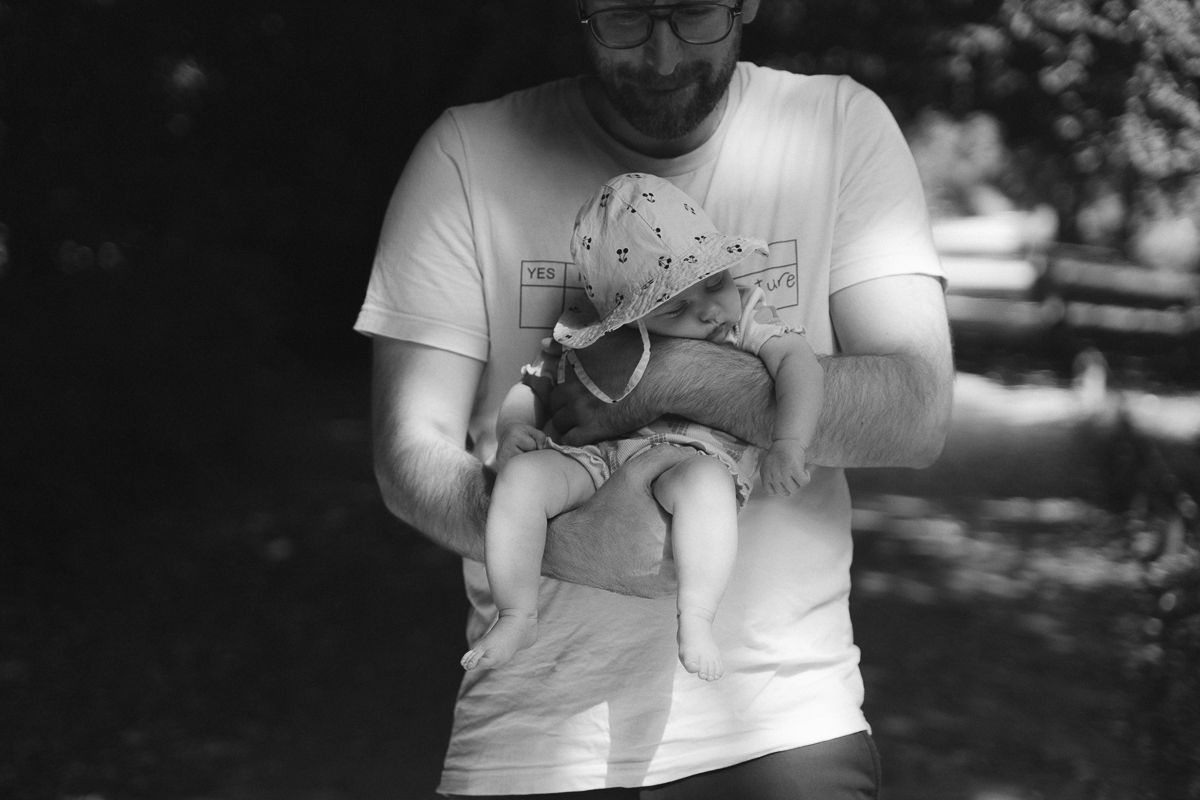 Die Nahaufnahme eines Vaters, der seine neugeborene Tochter im Arm hält, die während einer Newborn-Fotosession in Siegen entstand.