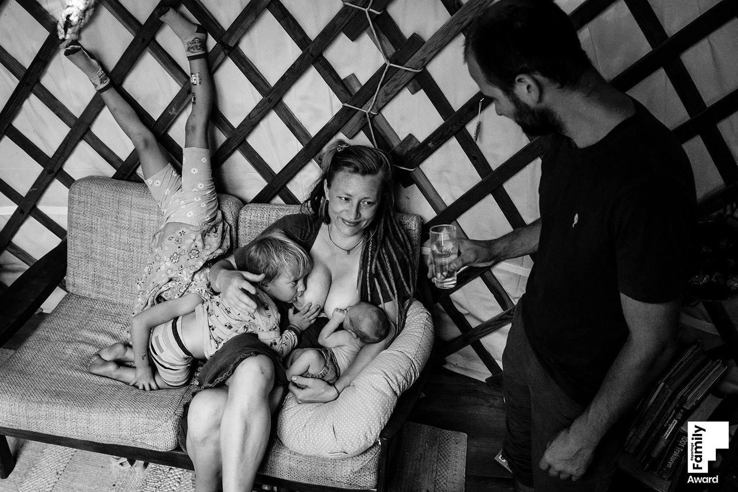 Der intime Moment in welchem der Familienvater seiner Frau ein Glas Wasser bringt, während sie ihre beiden Söhne in eioner Jurte stillt.
