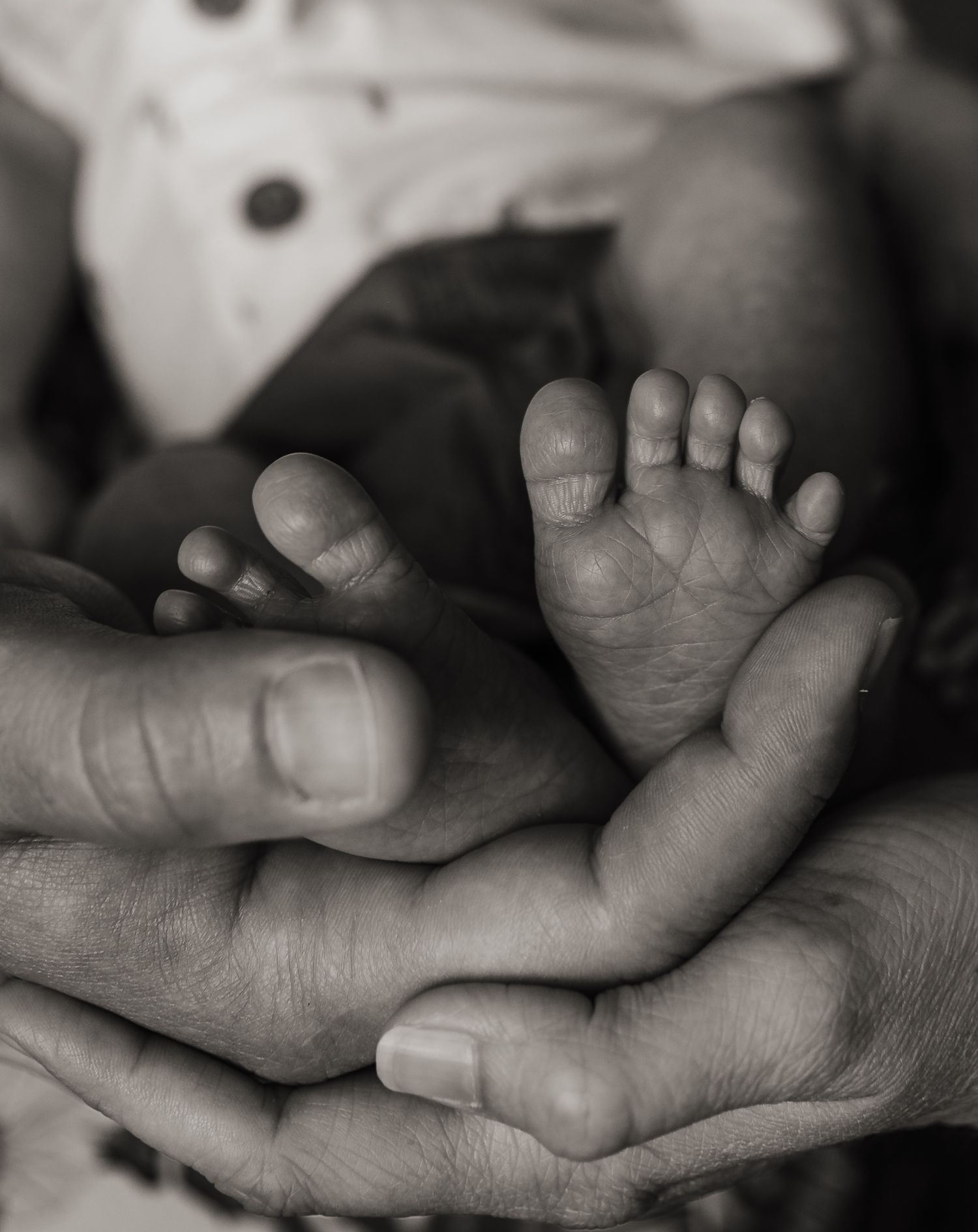 Black and white close-up series of a baby's tiny feet being held in an adult's hands.