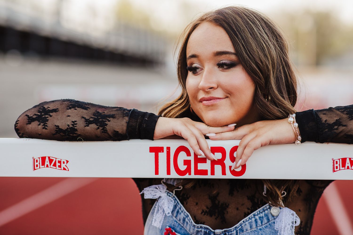 A student in black lace sleeves poses by a Tigers stadium sign.