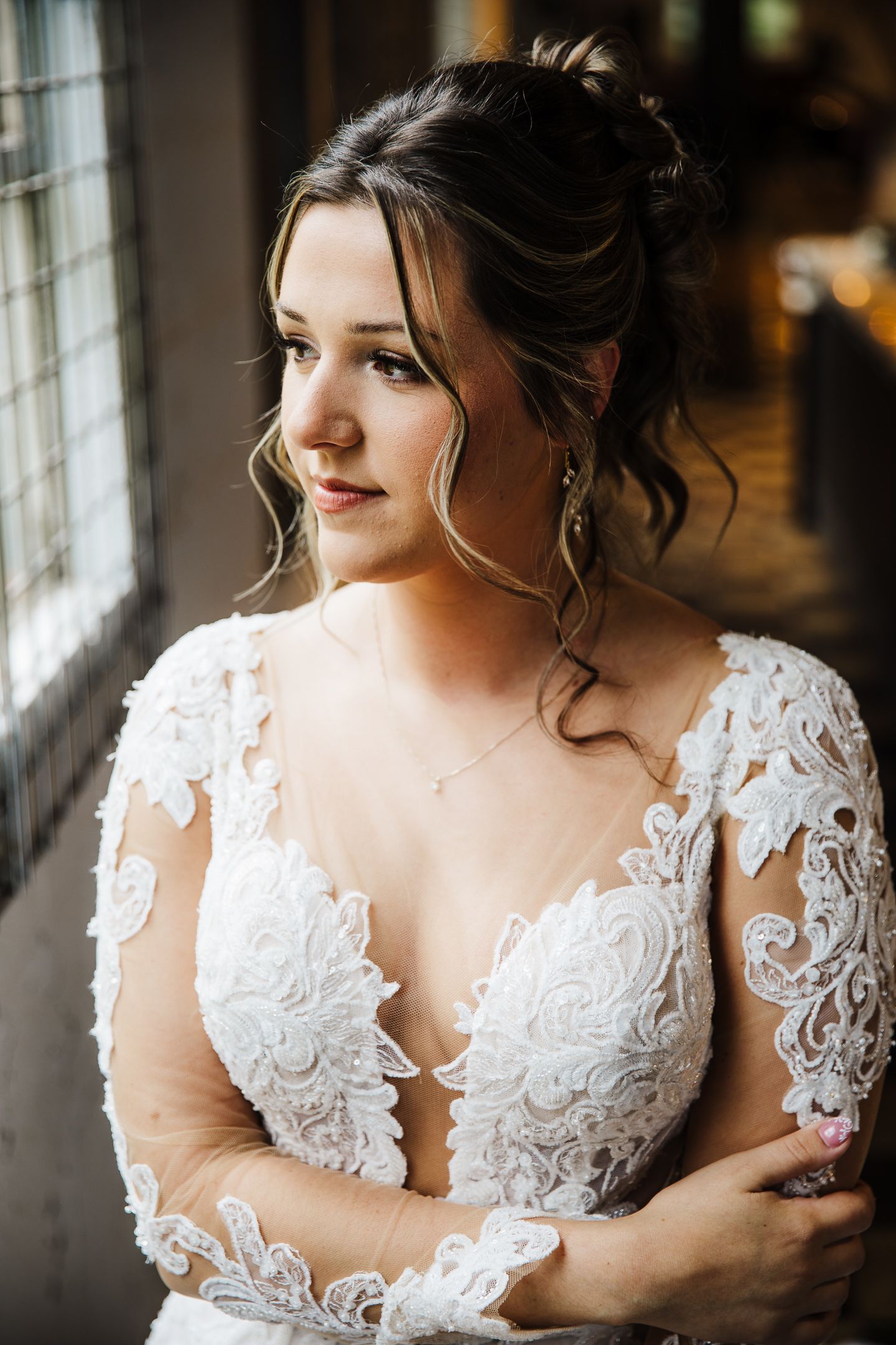 Close-up portrait shots of a bride in a white lace wedding dress with delicate details near a window.