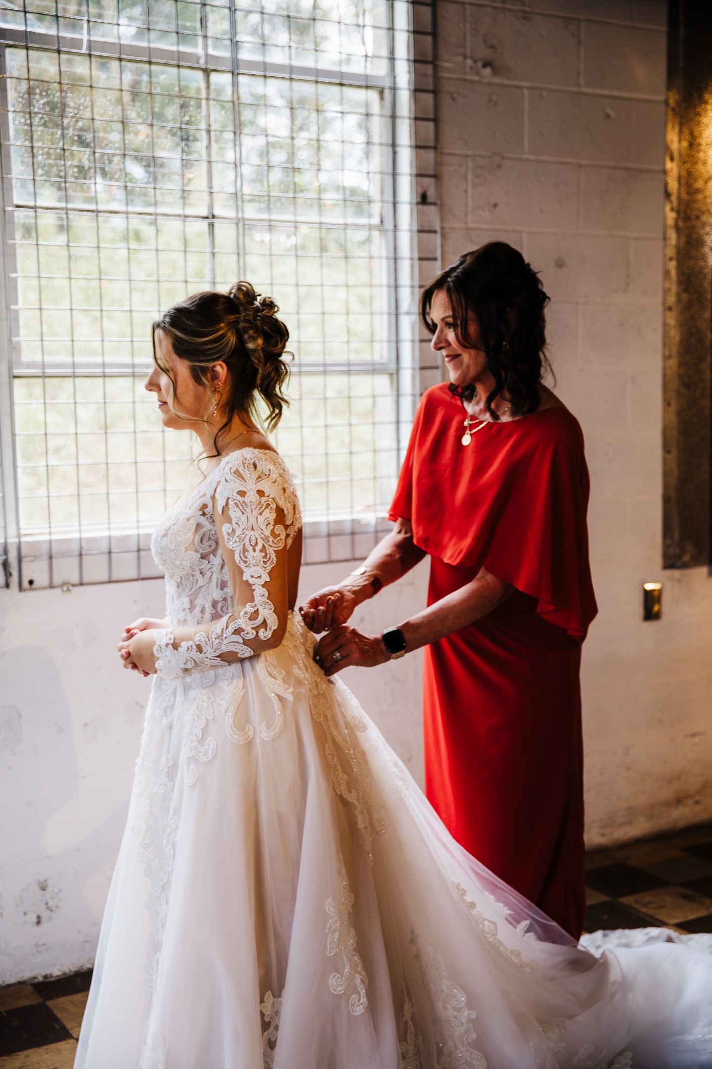 Wedding preparations in a bright room with white gown and red accent details.