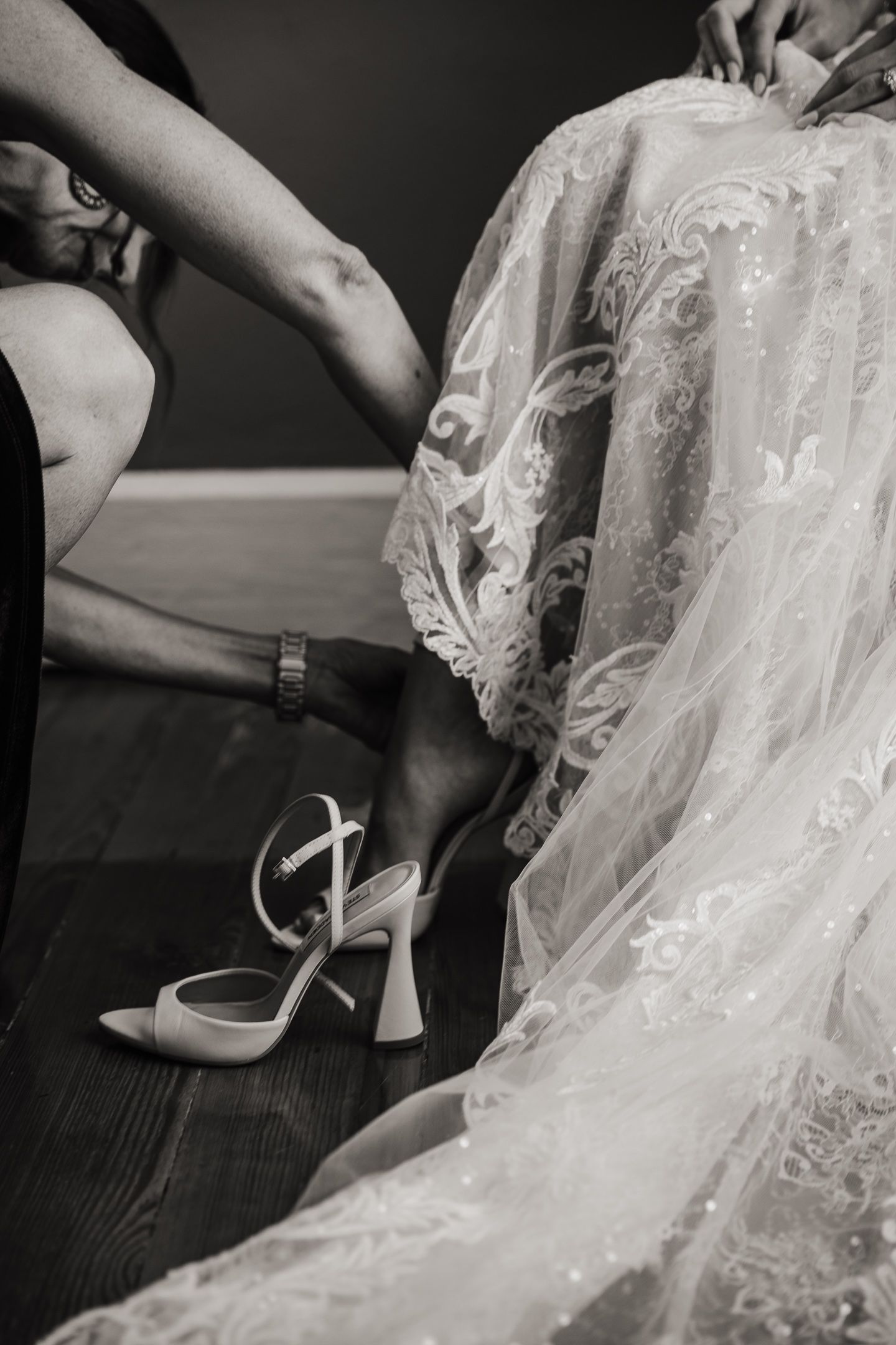 Close-up of white lace wedding dress detail and bridal shoes.