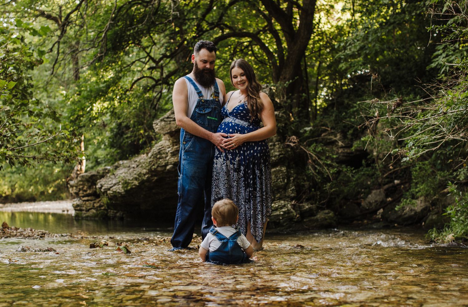 Family photo session in a lush green forest setting during golden hour.