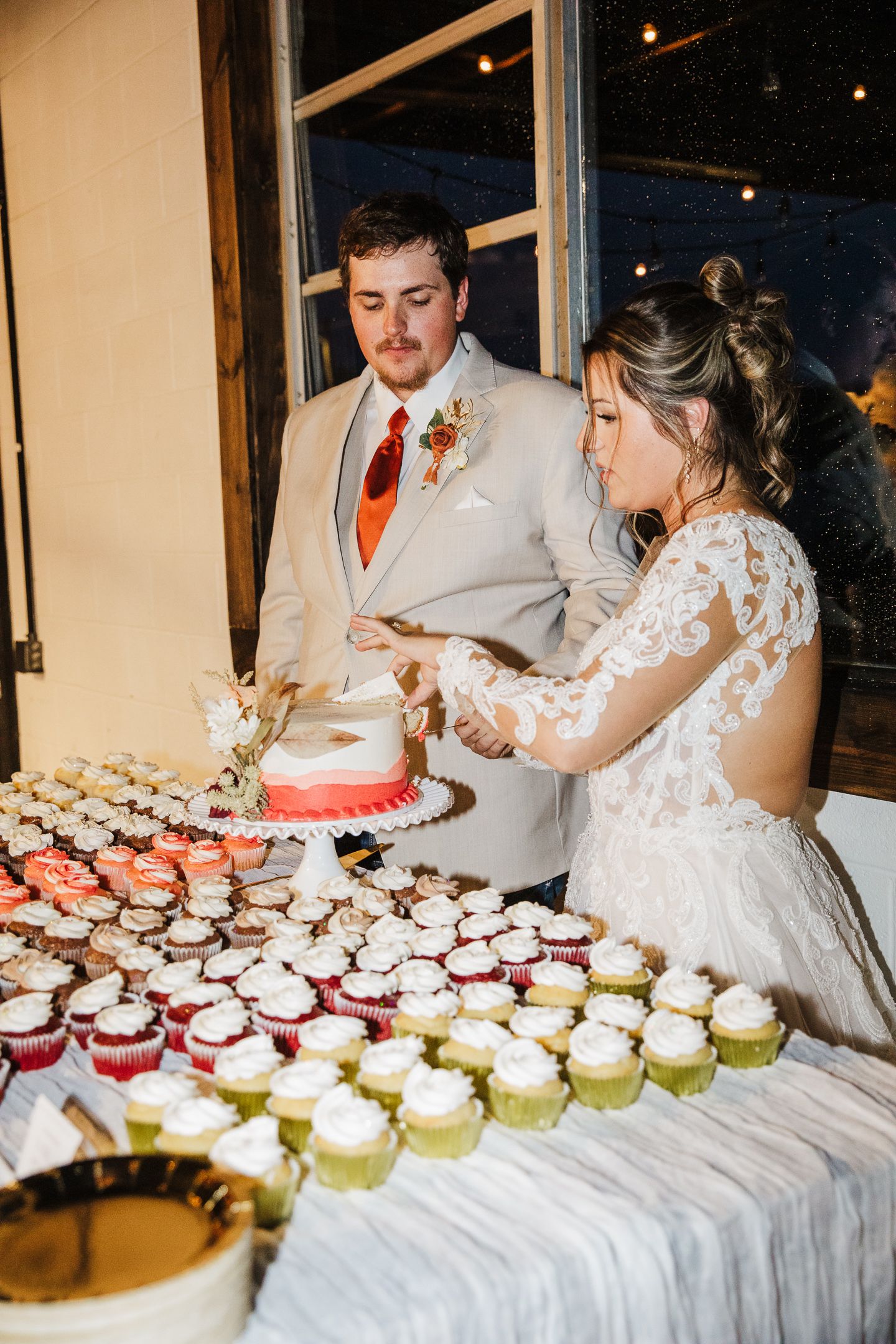 Wedding dessert table with cupcakes and cake cutting moment.