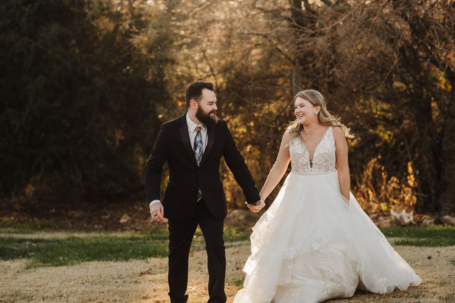 Wedding couple walking through a field during golden hour photography session.