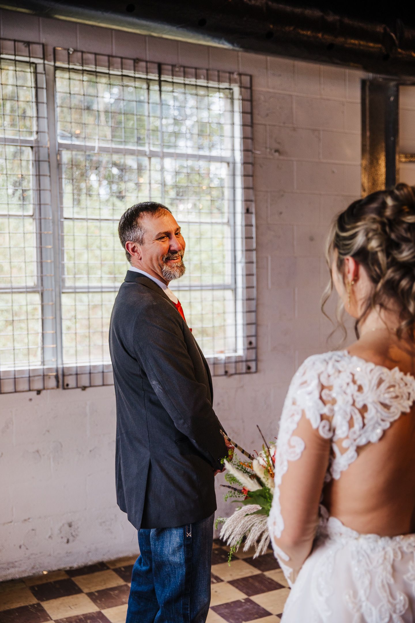 Emotional first look wedding moment captured in industrial space with natural window lighting.