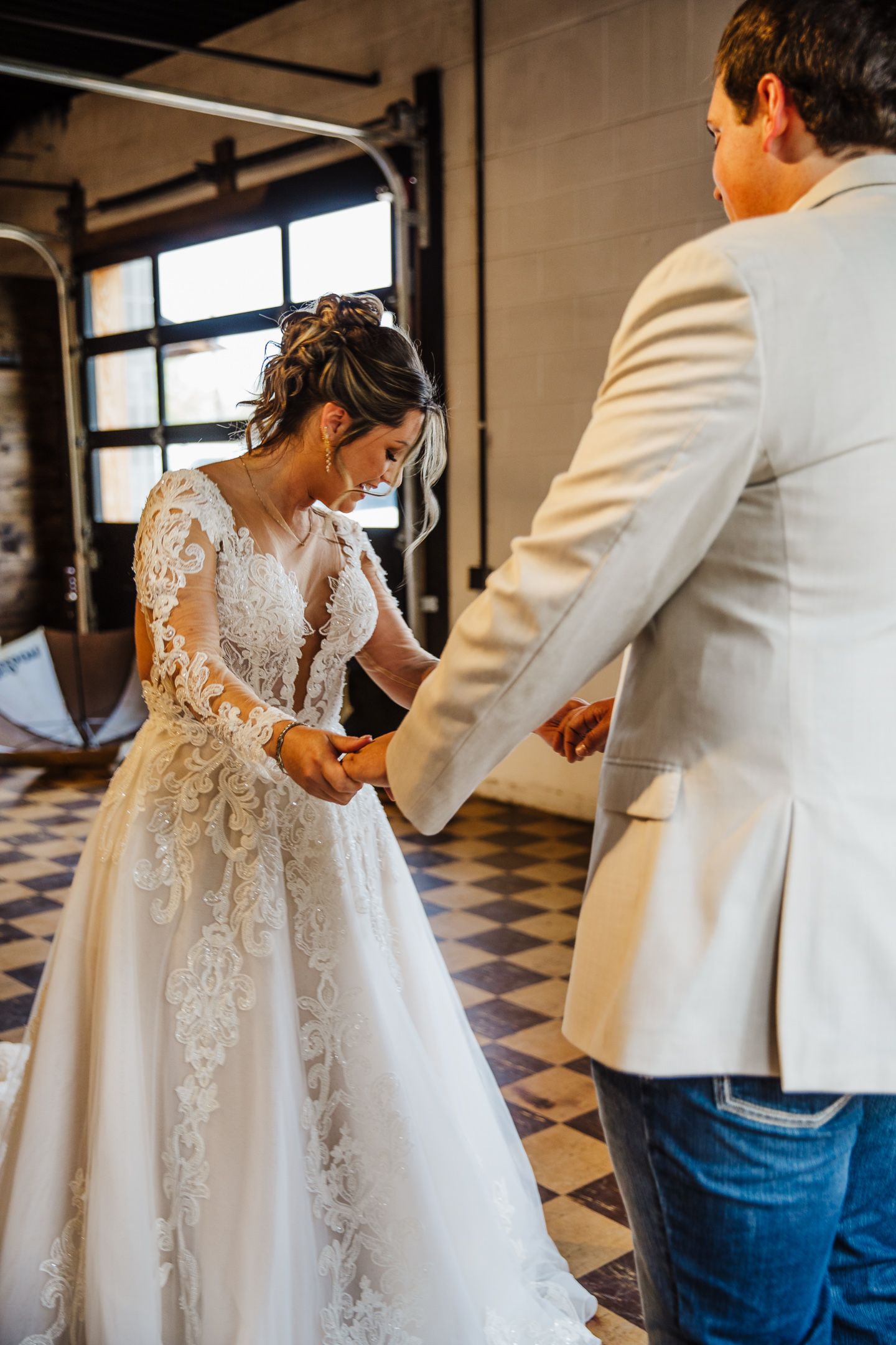Wedding dress fitting moment in an industrial space with checkered floors.