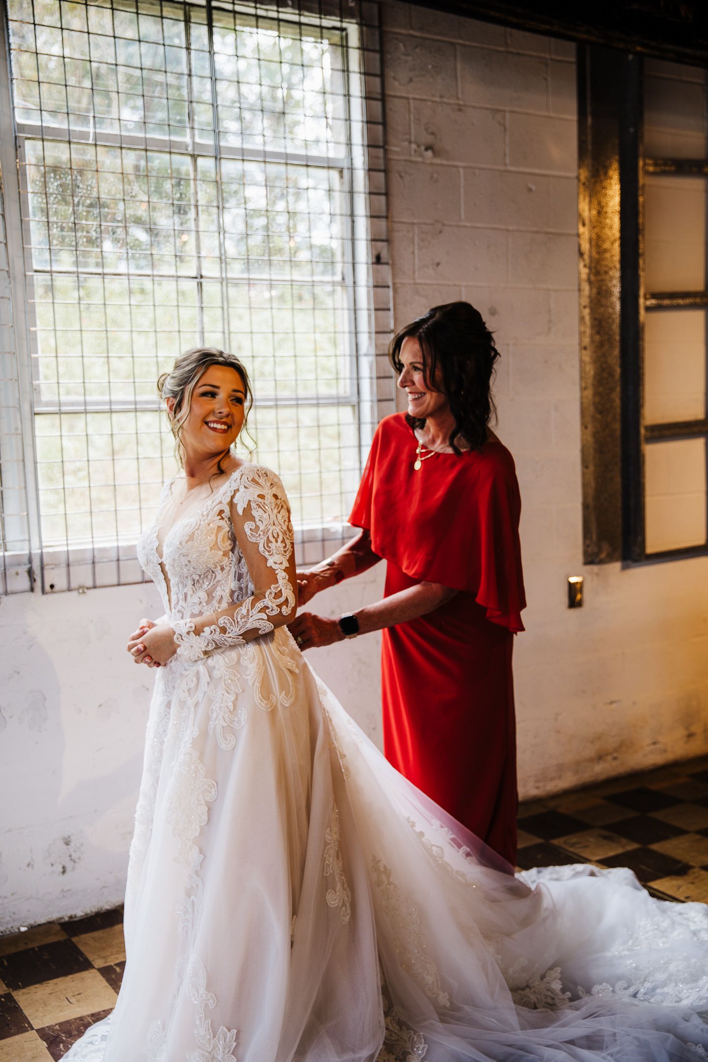 A beautiful wedding dress with lace details being adjusted in an industrial-style room.