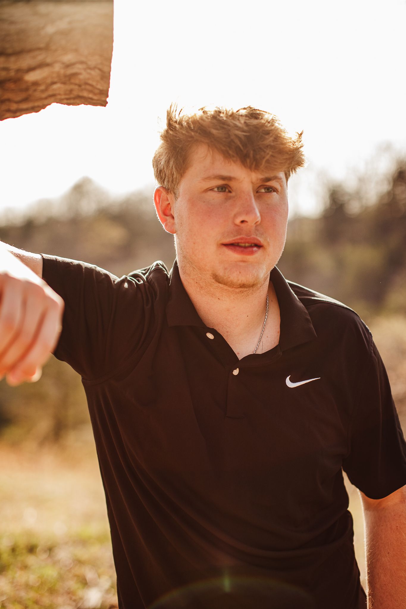 Person in black Nike shirt poses outdoors in warm sunset lighting.