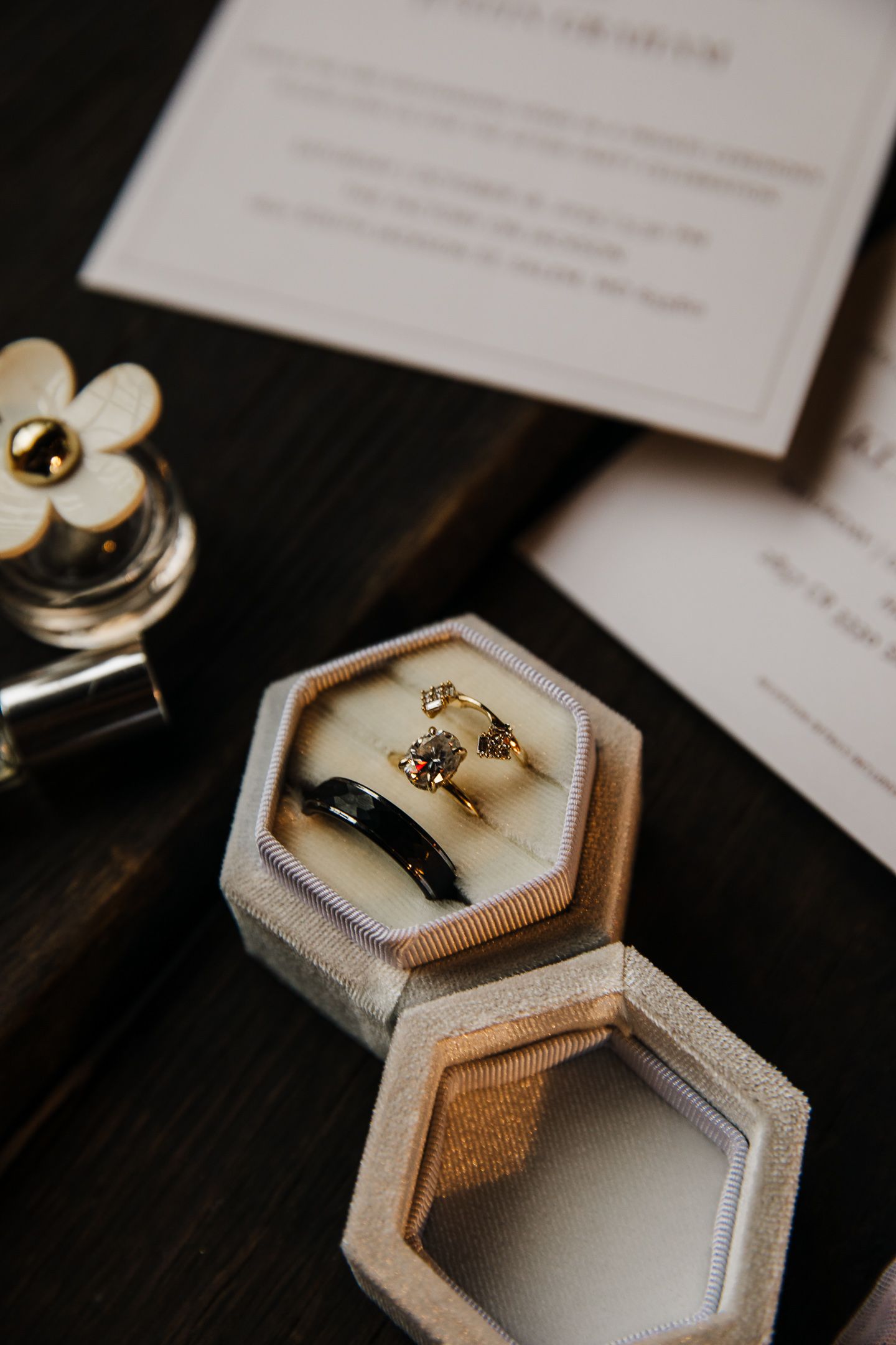 Wedding rings displayed in elegant hexagonal jewelry boxes on a dark surface.