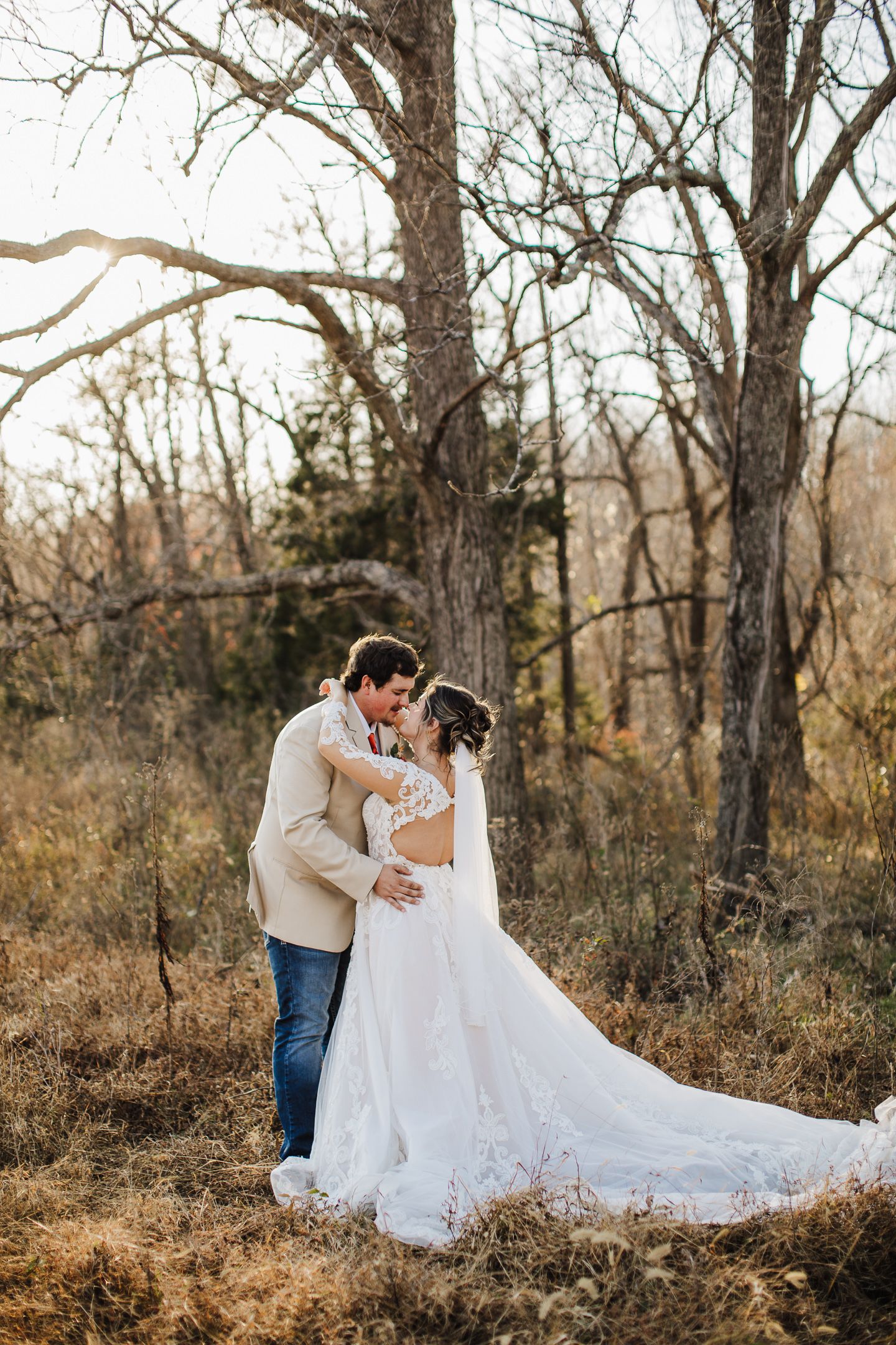 Romantic outdoor wedding portraits among bare winter trees in natural setting.