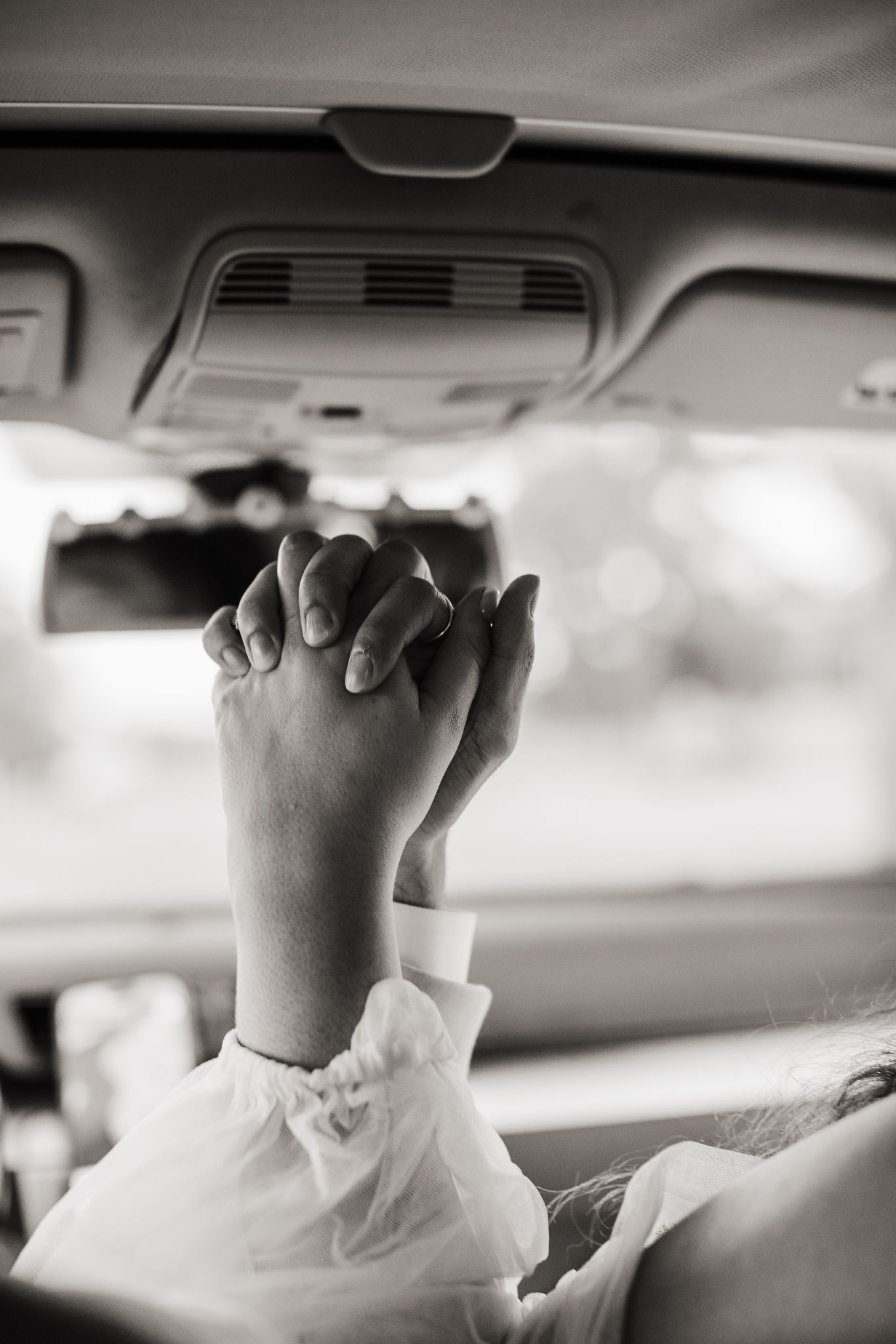 Black and white detail shots of hands holding onto car interior handles.