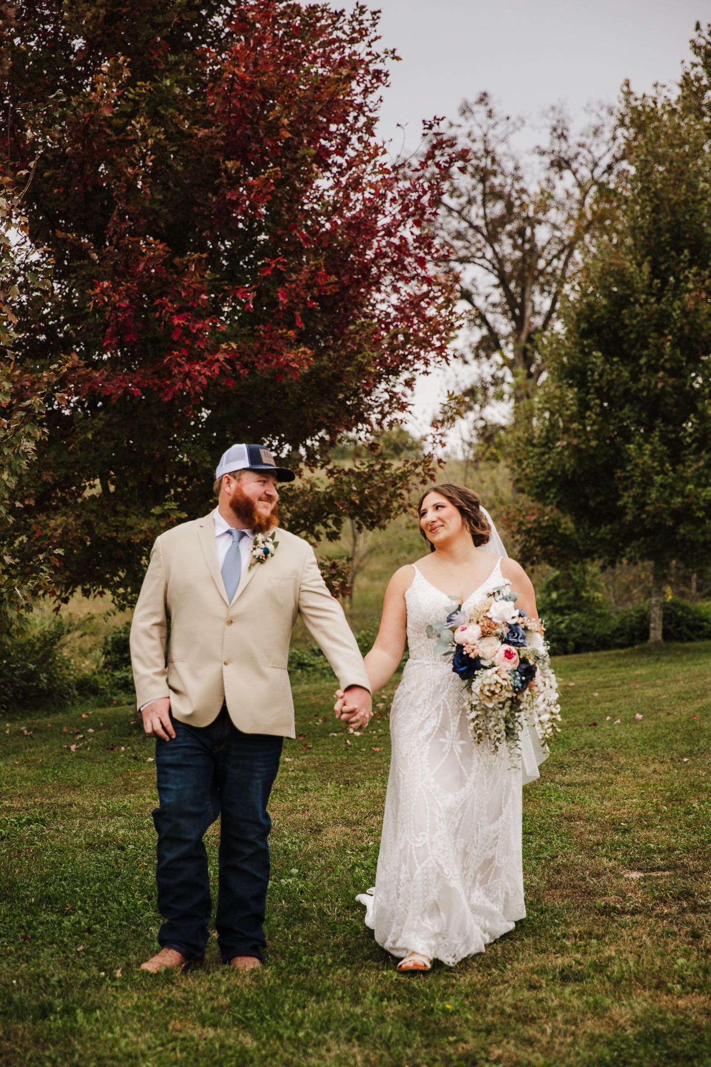 A couple shares a romantic moment in a fall garden setting with vibrant red foliage and lush greenery.