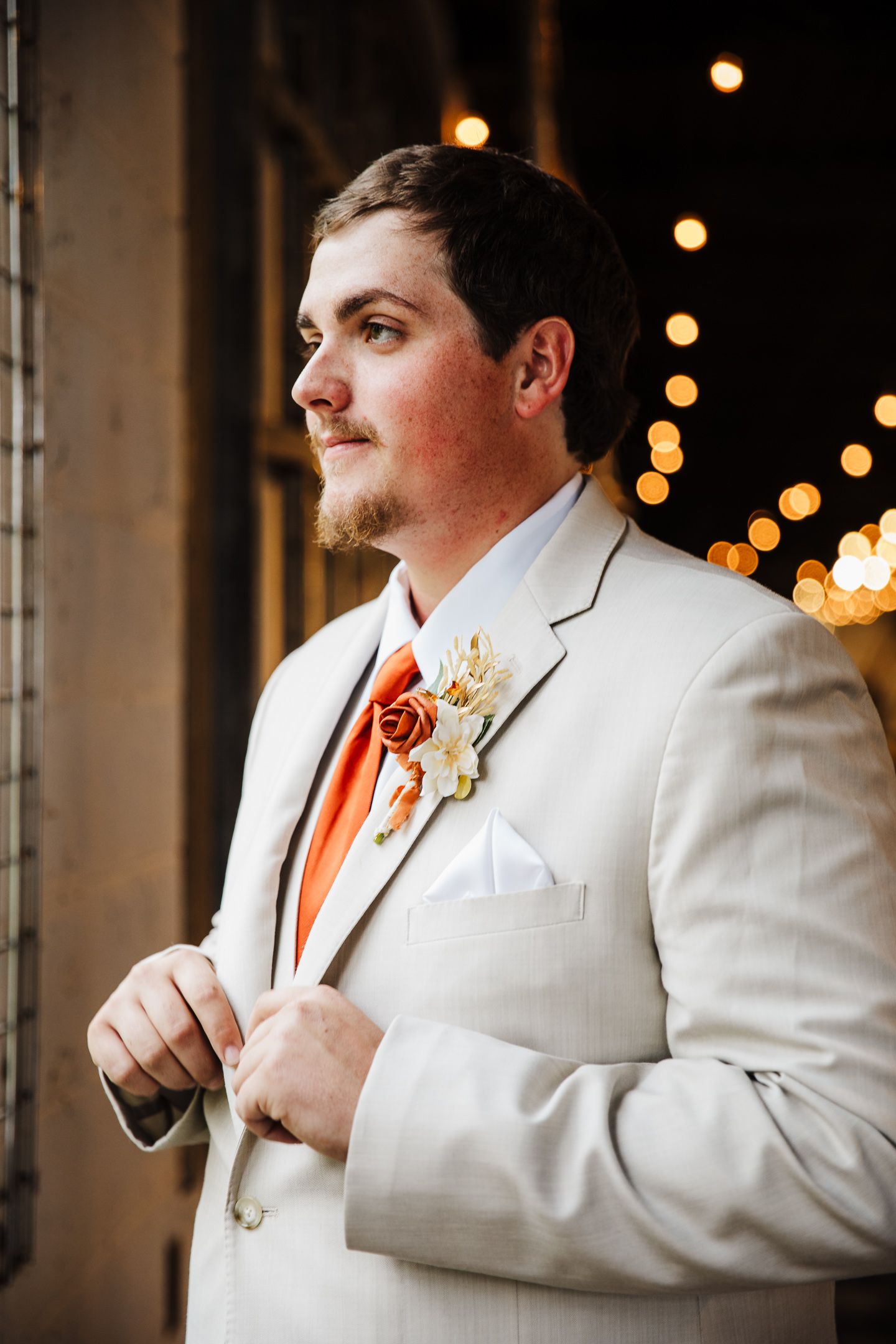A series of photos showing a groom in a white suit jacket and orange tie adjusting his boutonniere against a blurred background.