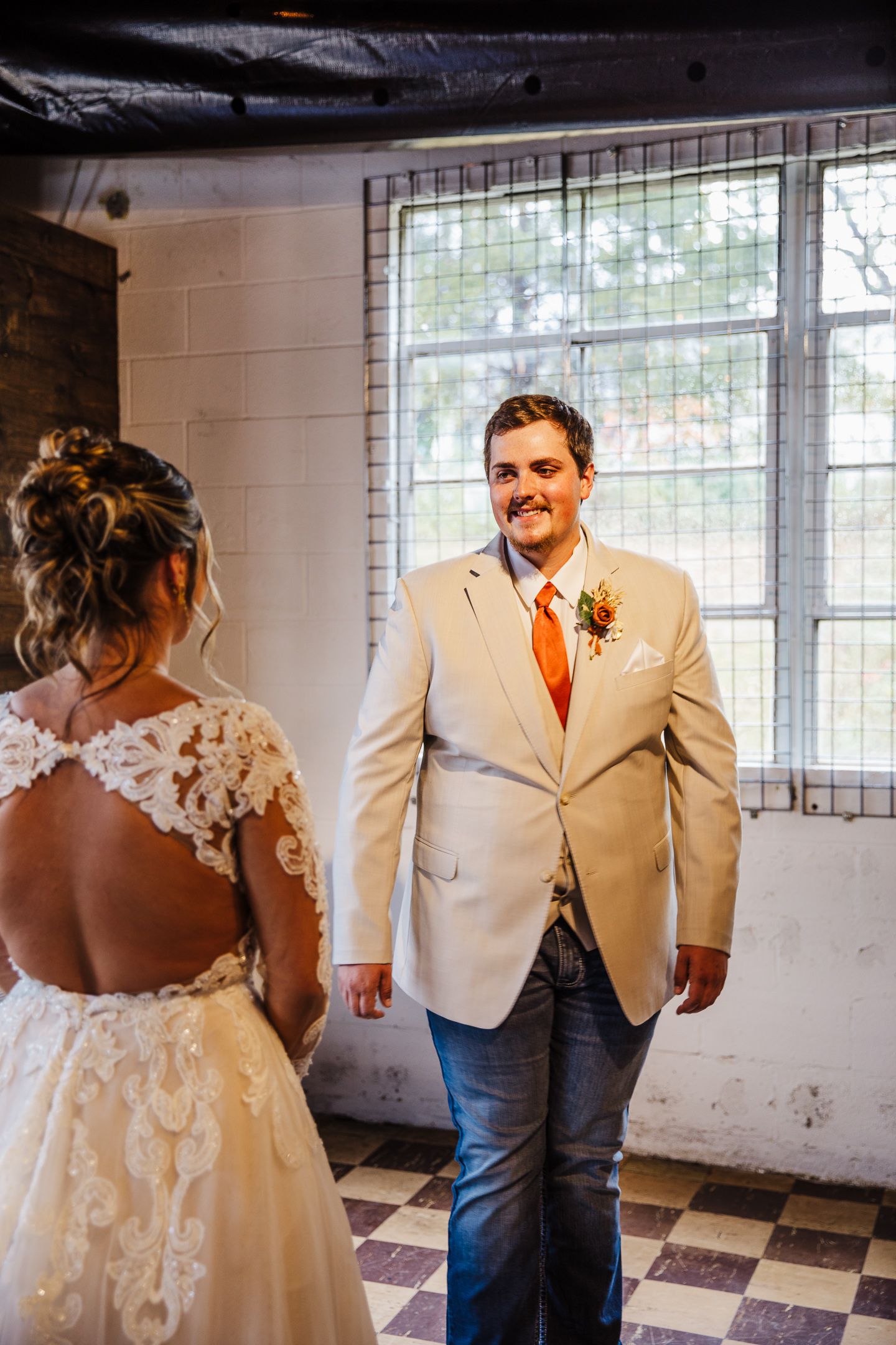 First look wedding moment in industrial venue with checkered floor and white brick walls.