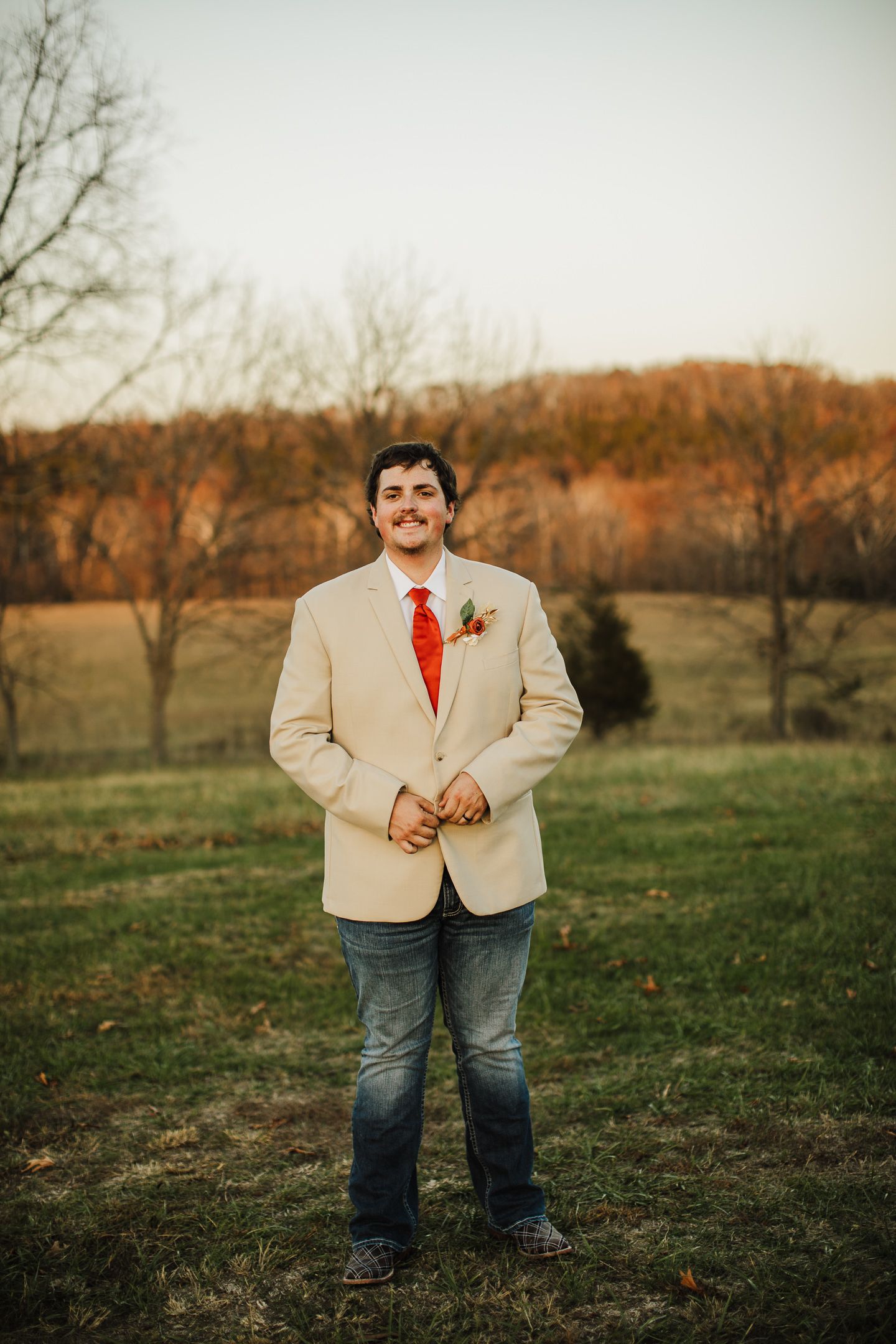 An autumn outdoor portrait session in a field with bare trees and golden light.