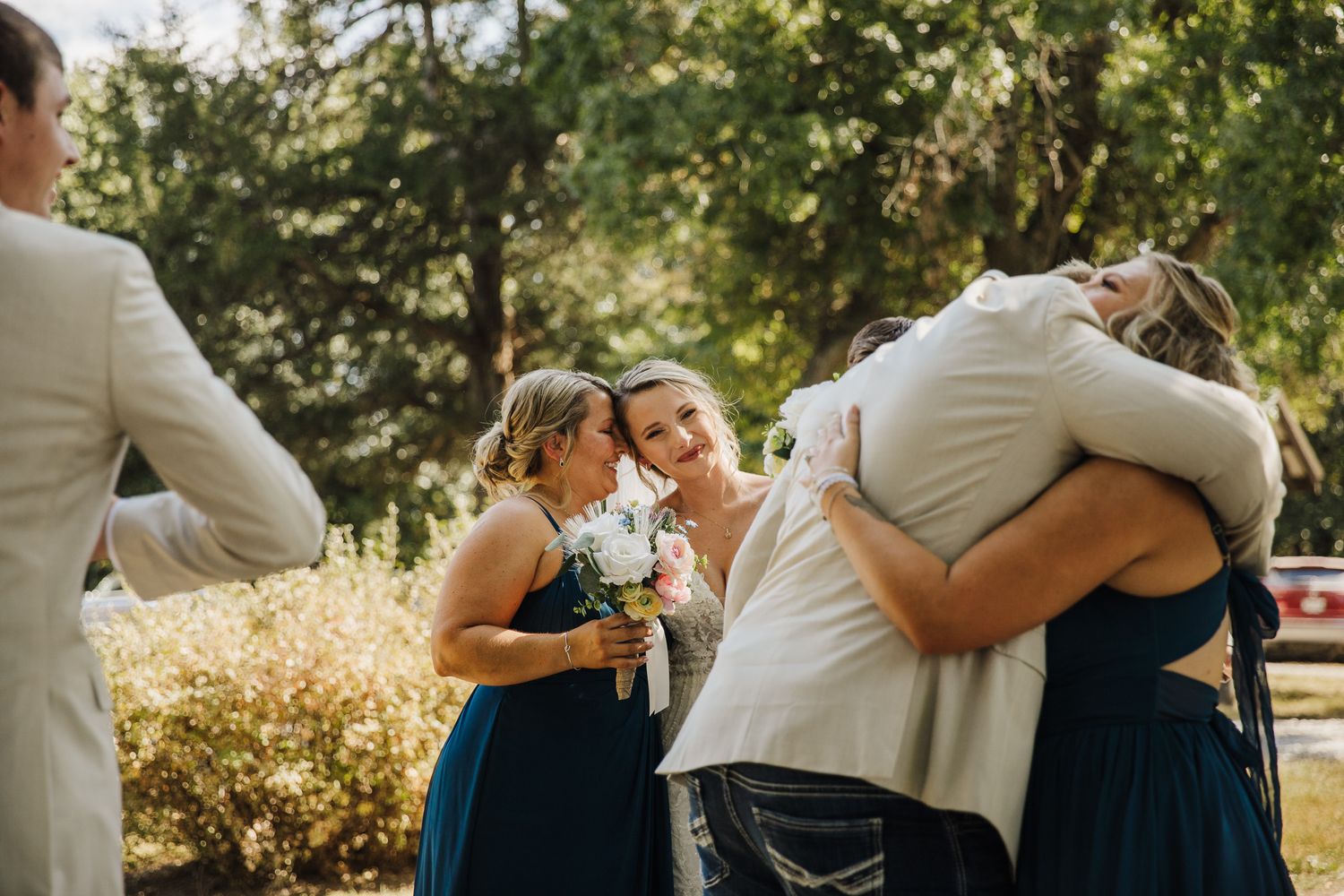 Wedding party shares emotional embraces and celebrations outdoors.