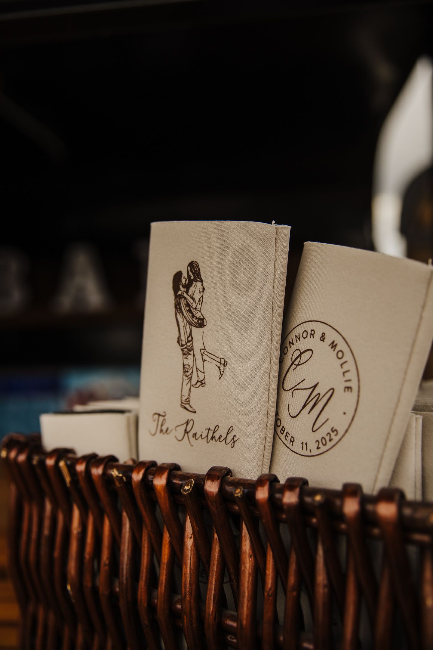 Vintage paper place cards with handwritten names arranged in a row against a dark background.