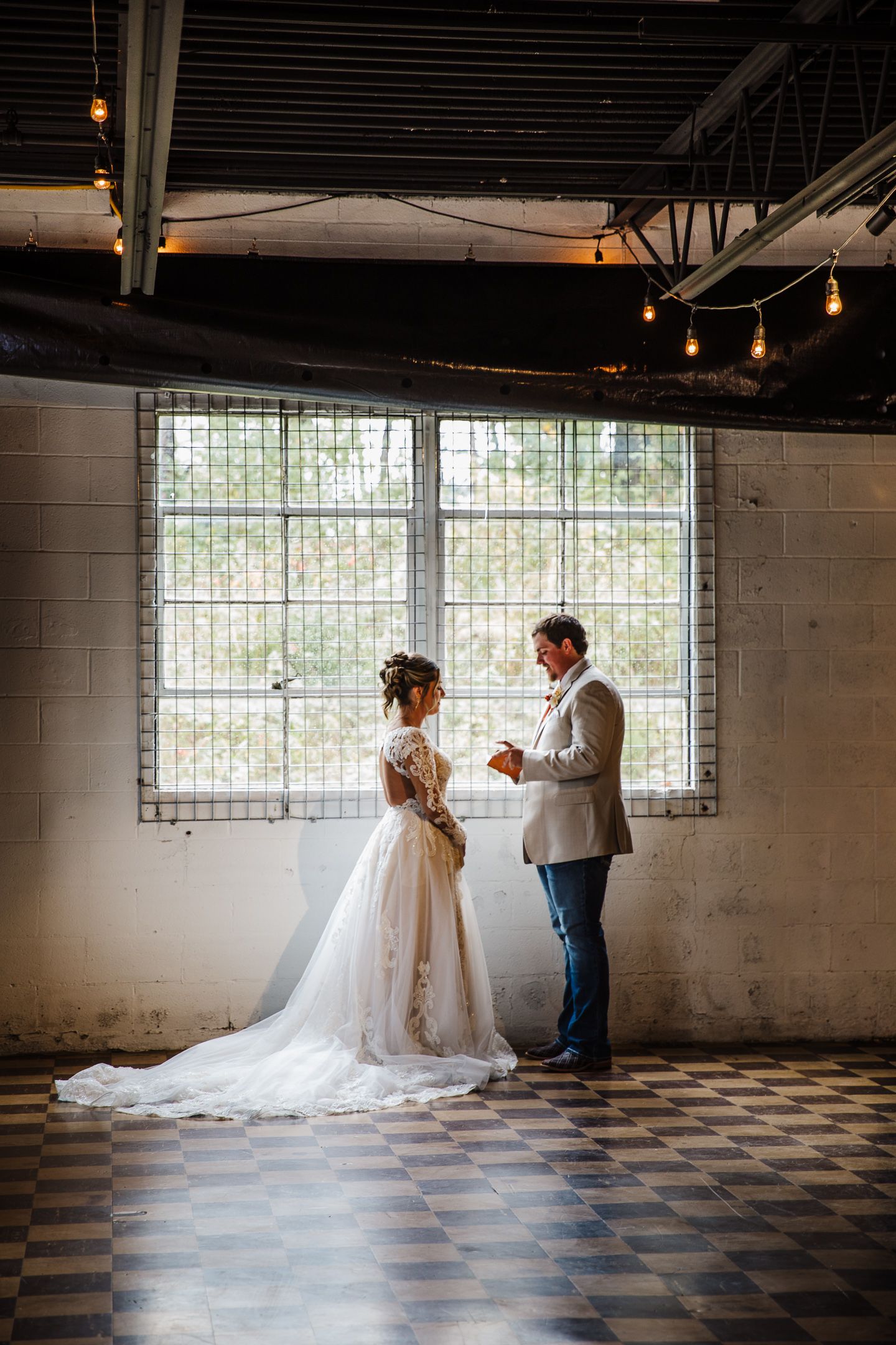 Romantic wedding photo session in industrial venue with checkered floor and natural lighting.