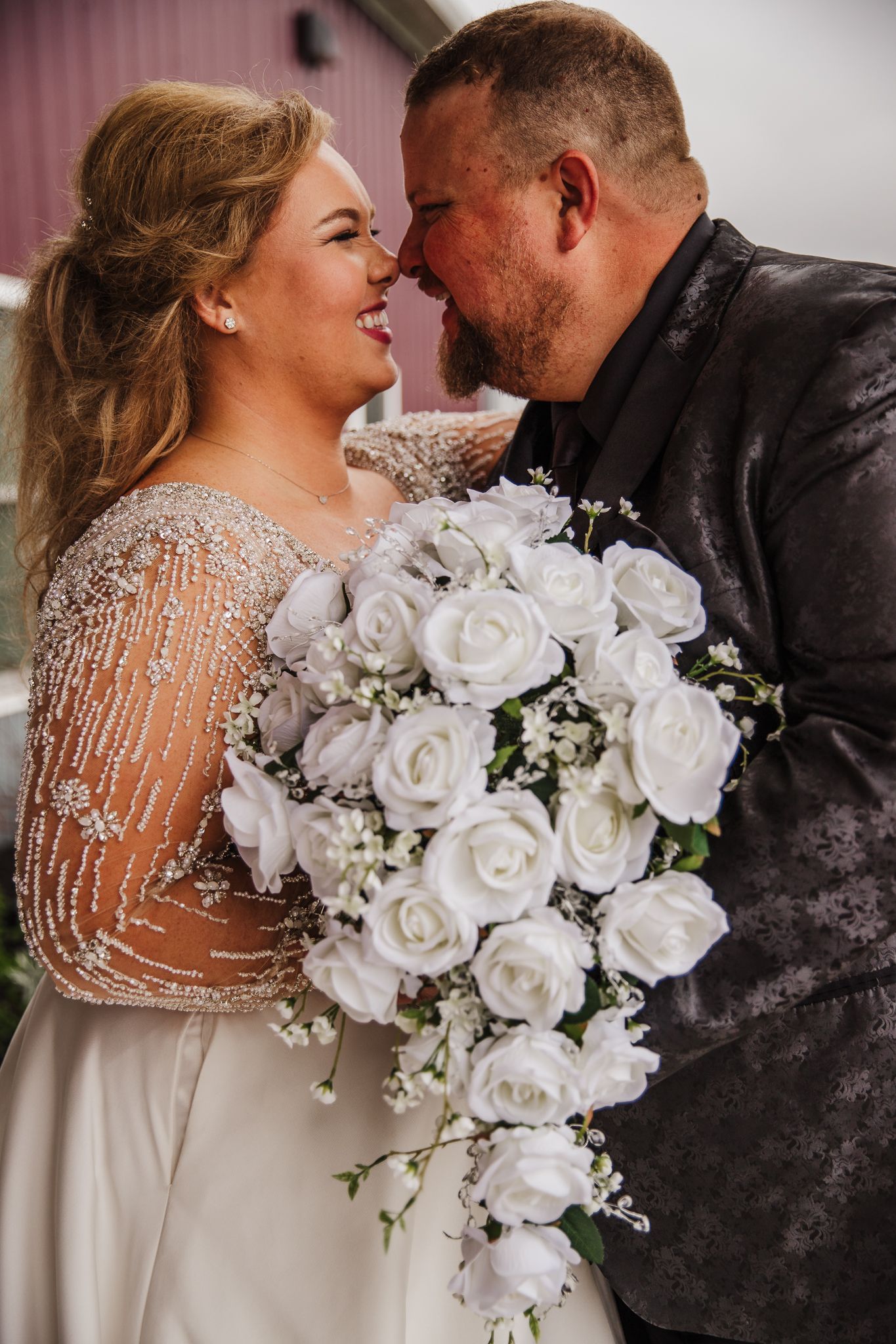 Elegant white rose wedding bouquet with beaded dress details in romantic indoor setting.