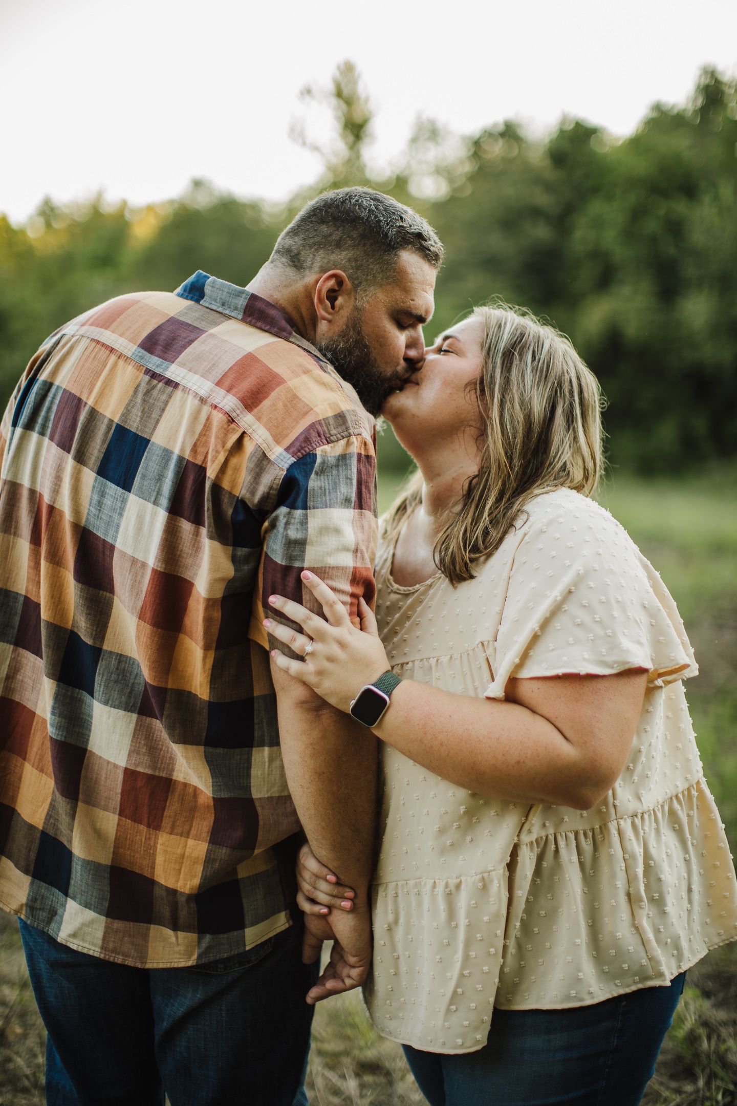 A couple embraces and shares tender moments in casual attire outdoors.