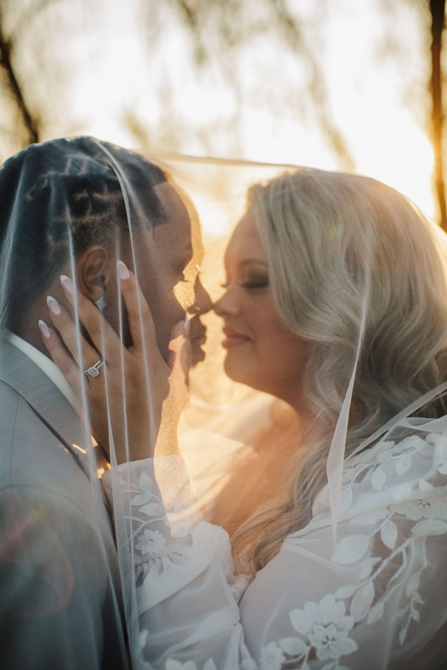A romantic wedding portrait of a couple sharing an intimate moment at sunset.